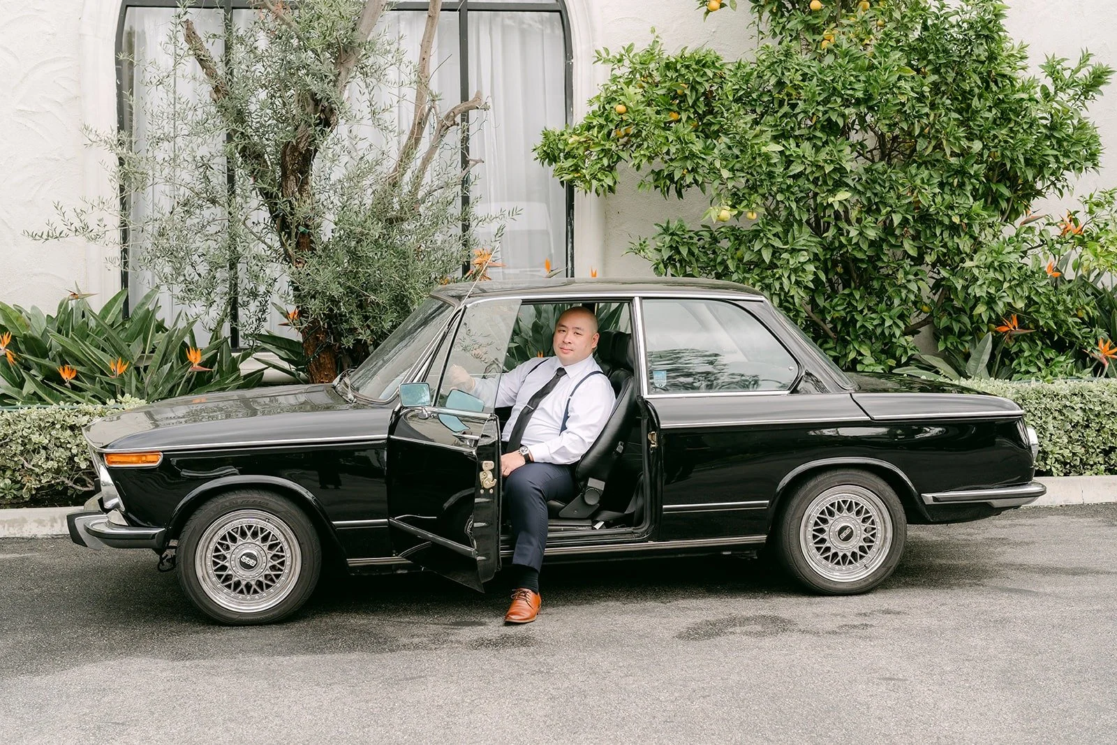 Yao leaning out of a vintage black car at The Villa