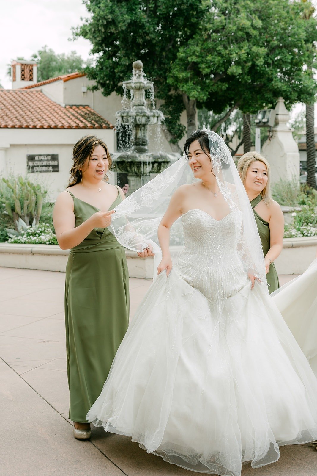 A bridesmaid lifts Eunice's veil as she laughs