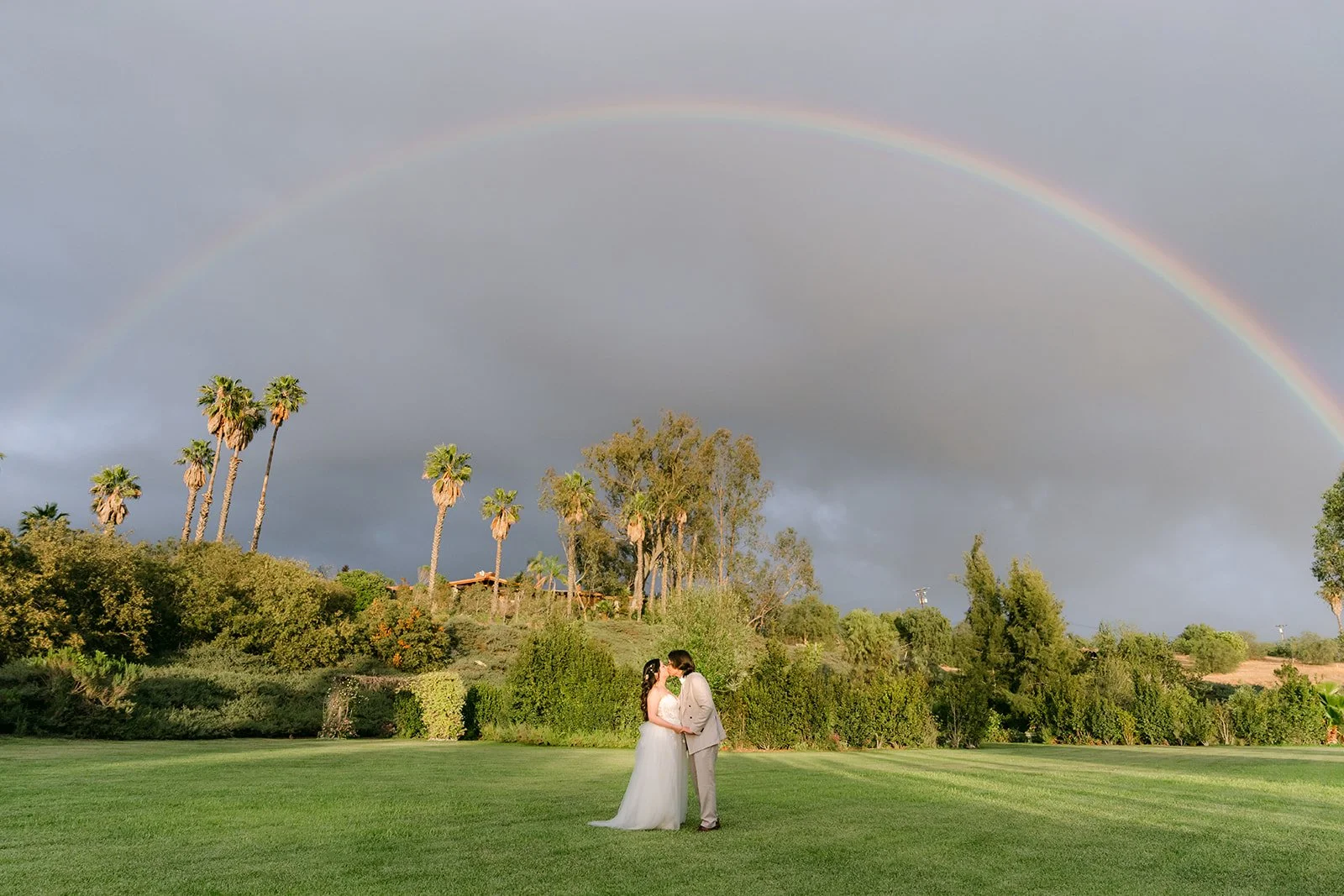 Rainbow arching over the couple and the palm trees in Escondido