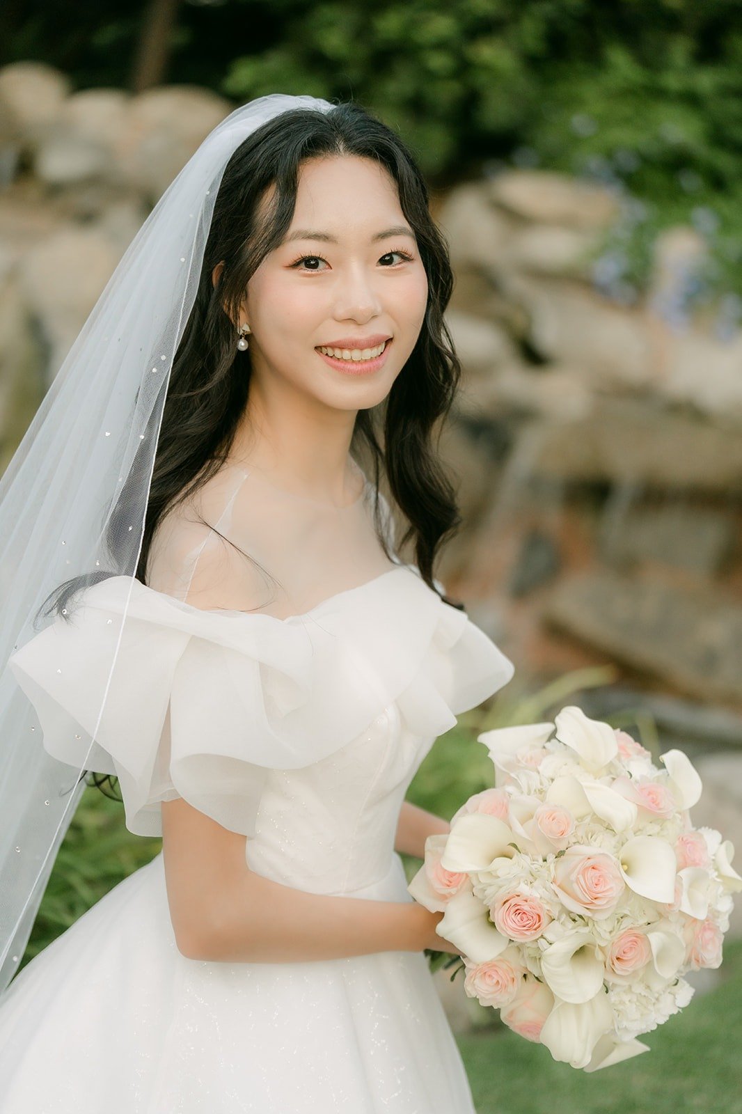 Jeannie with her bouquet by the waterfall rocks