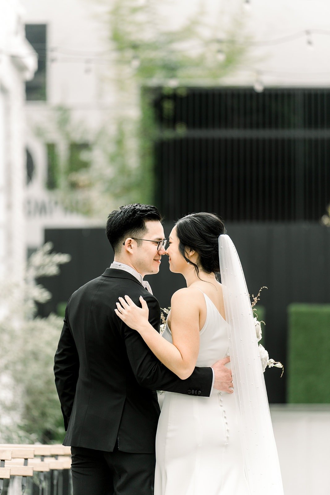 Cindy and Alex embrace by the green hedge