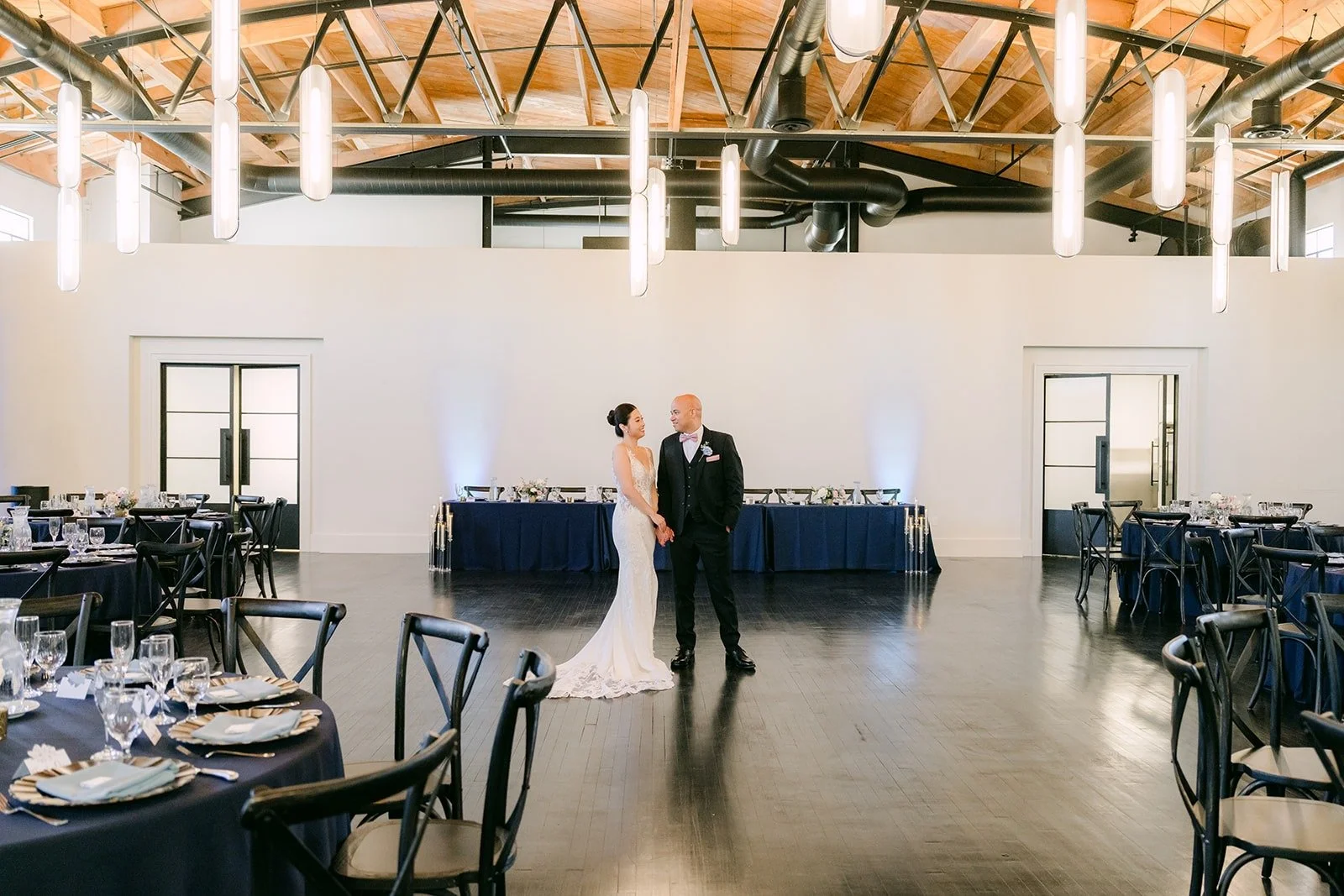 Elisa and Brandon alone in the empty reception room under the wood beam ceiling
