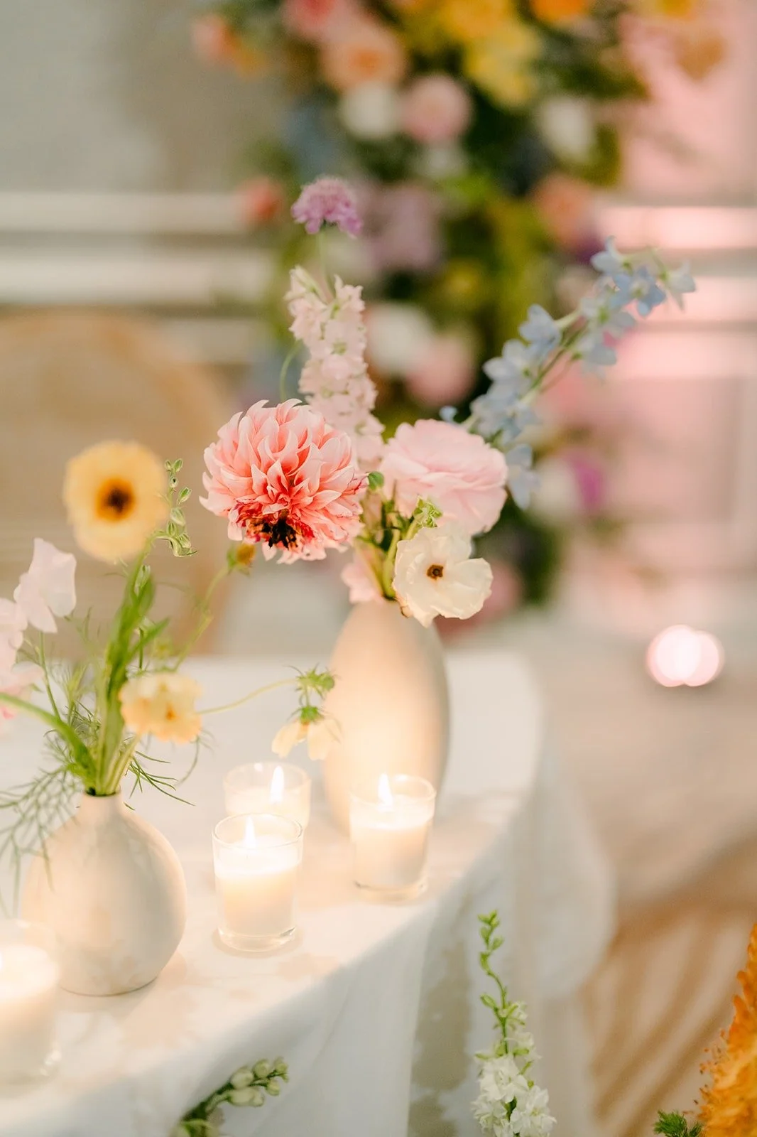 A guest table centerpiece of peach dahlias and candles