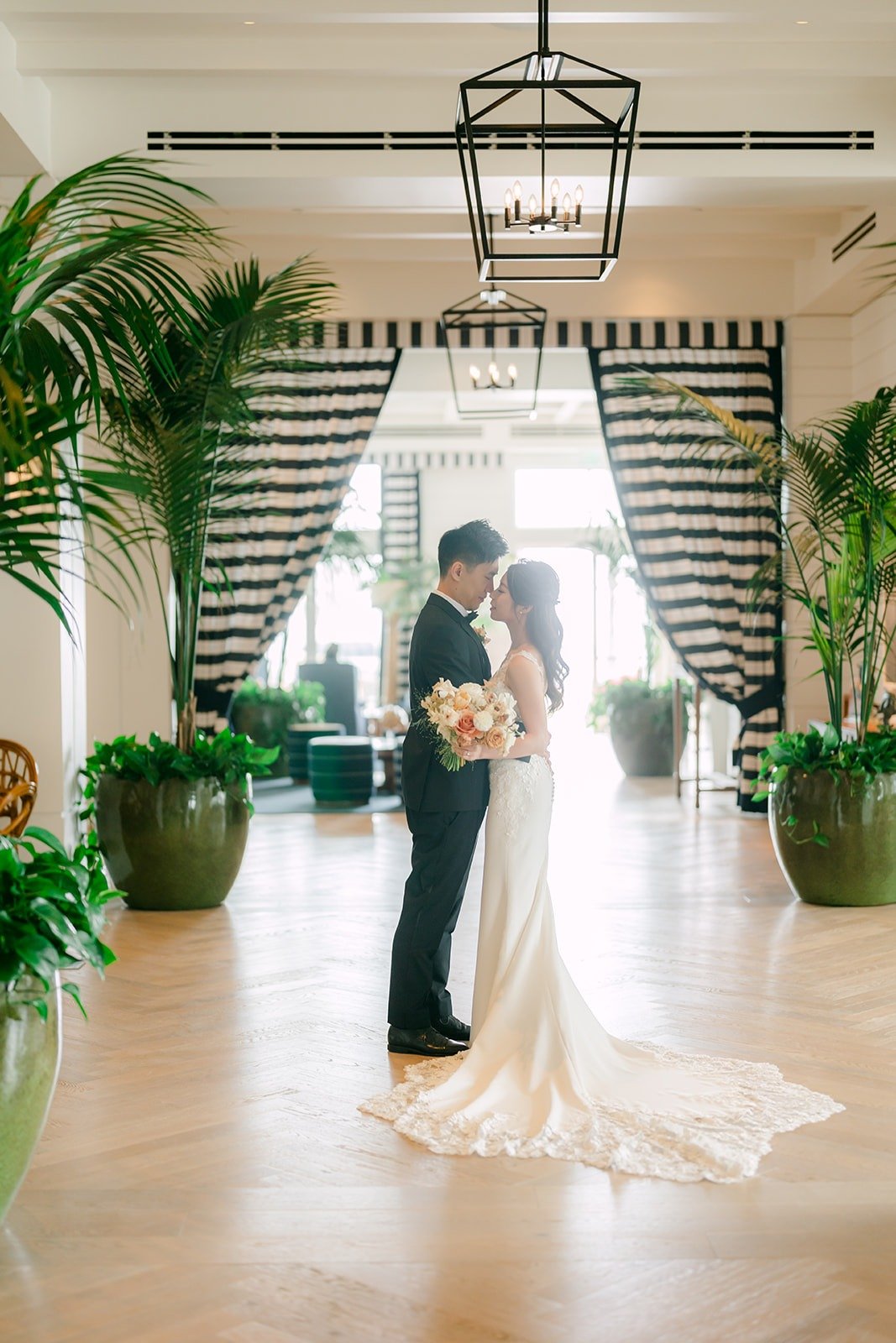 Angela and Eli in a Seabird hallway lined with palms and striped drapes