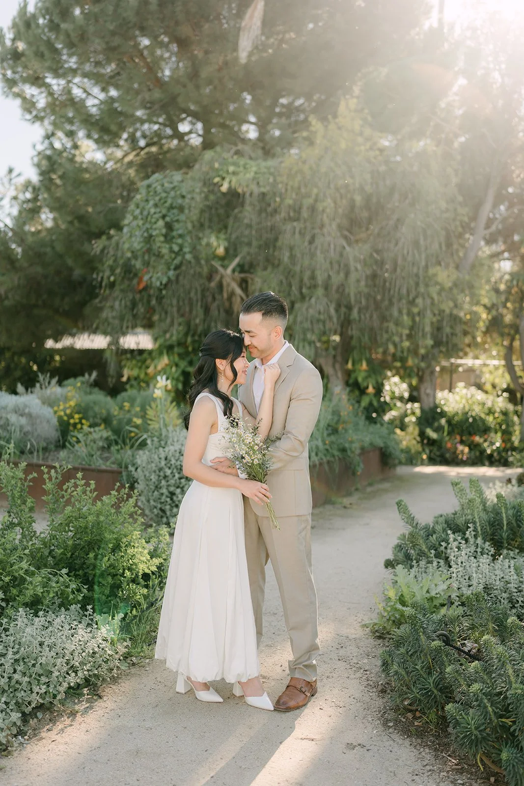 Kim and Vincent walking hand in hand down a sunlit garden path.