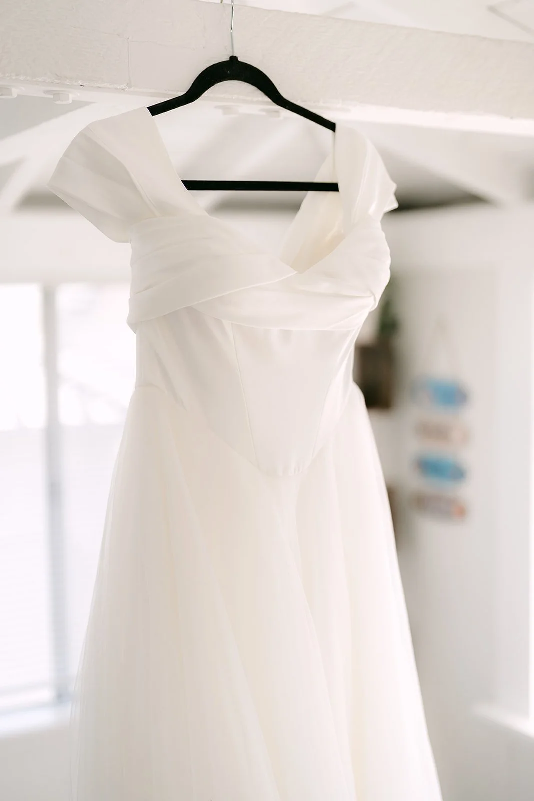 Jadee's wedding gown hanging in the bright Newport Beach rental