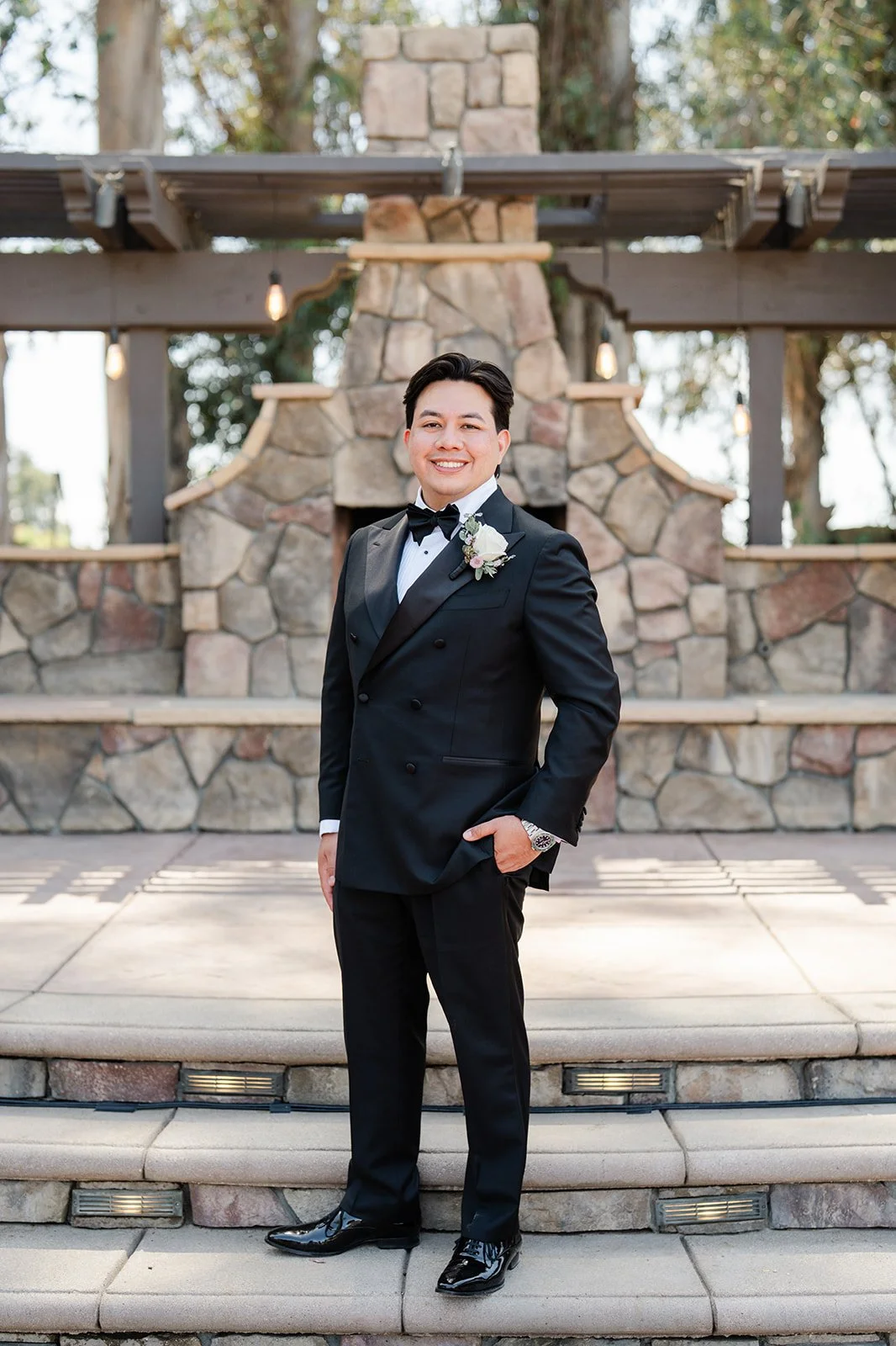 Groom standing in front of the stone fireplace at The Walnut Grove