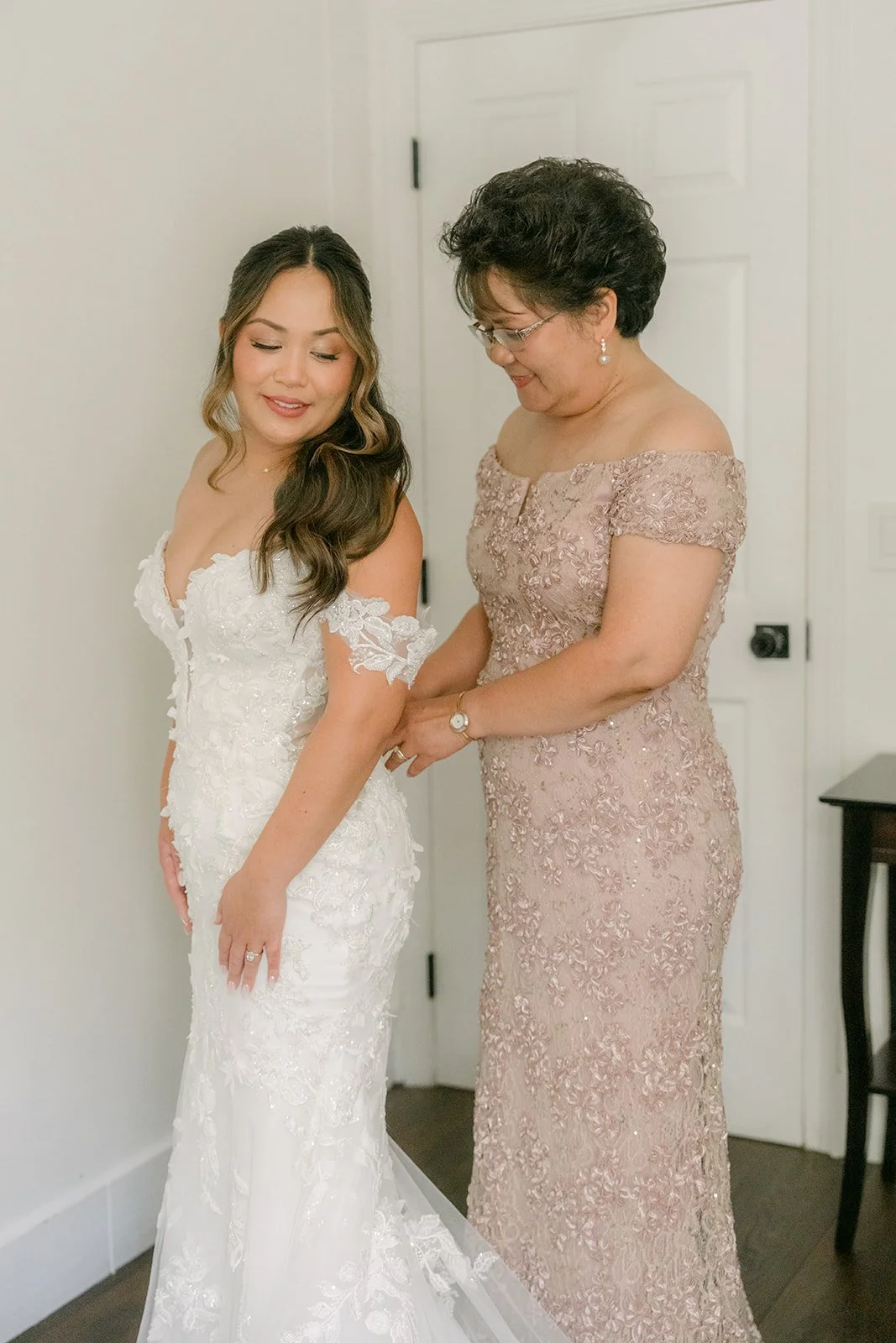 A loved one helping Nicole with the off the shoulder sleeves of her gown.