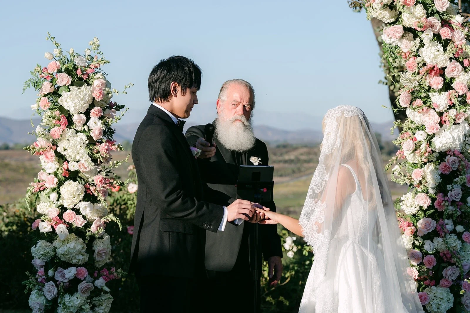 Konitha and Job holding hands at the floral arch