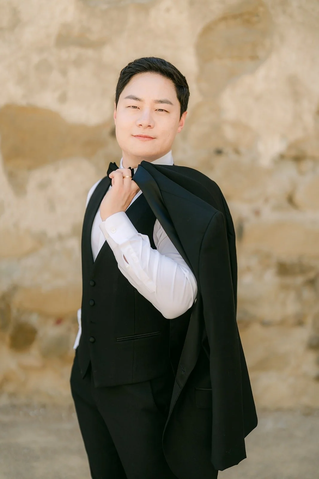 Min Soo posing with his tuxedo jacket over one shoulder