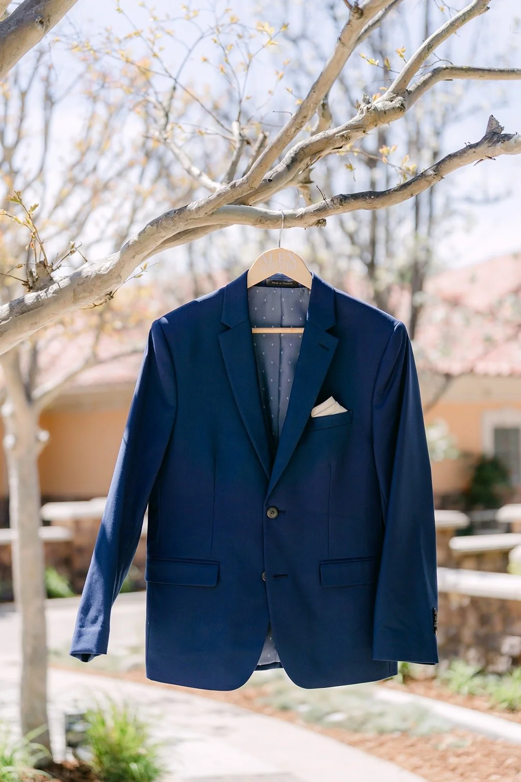 Alex's navy suit hanging from a tree branch at Los Robles Greens