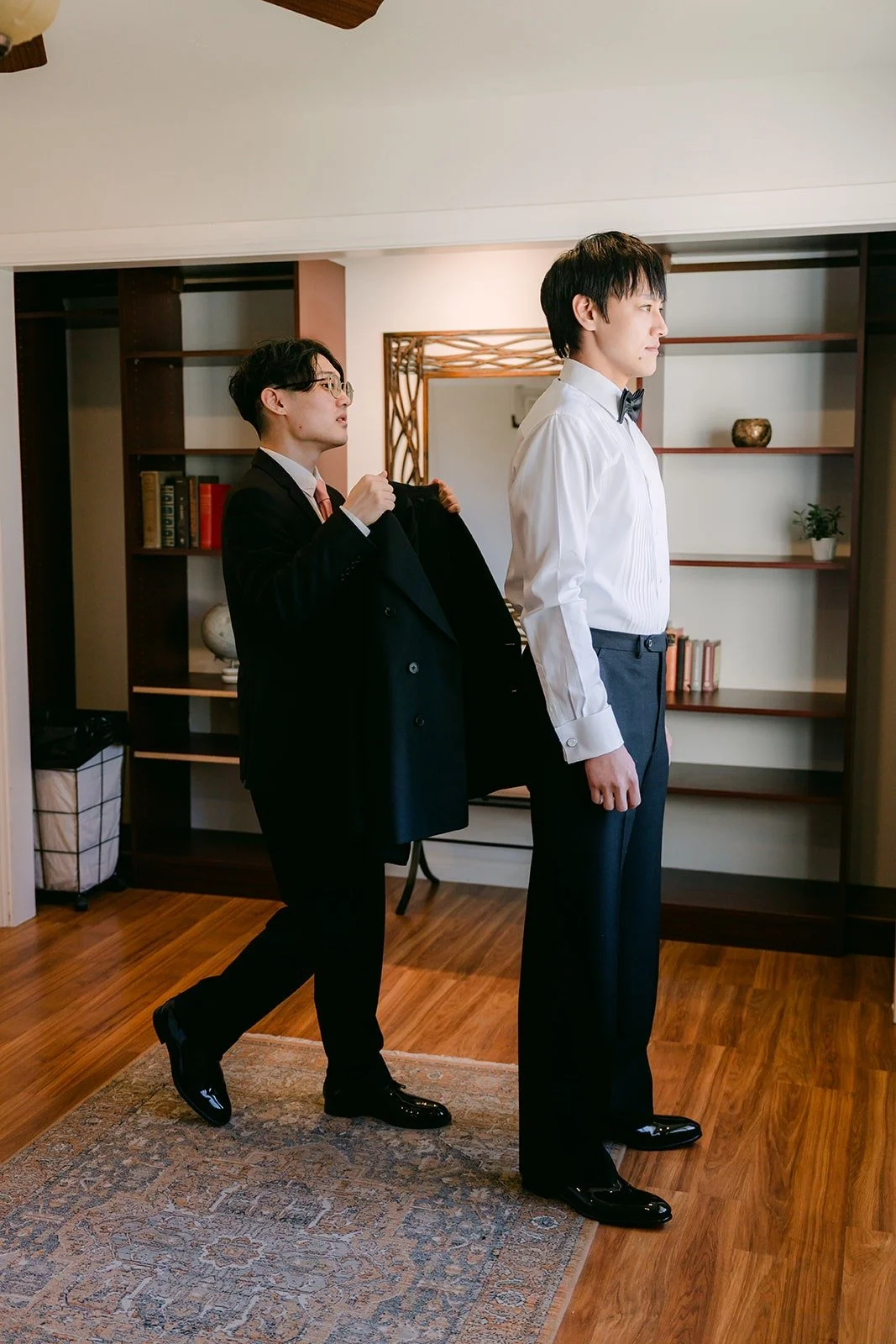 Job getting into his black tuxedo in the groom's suite