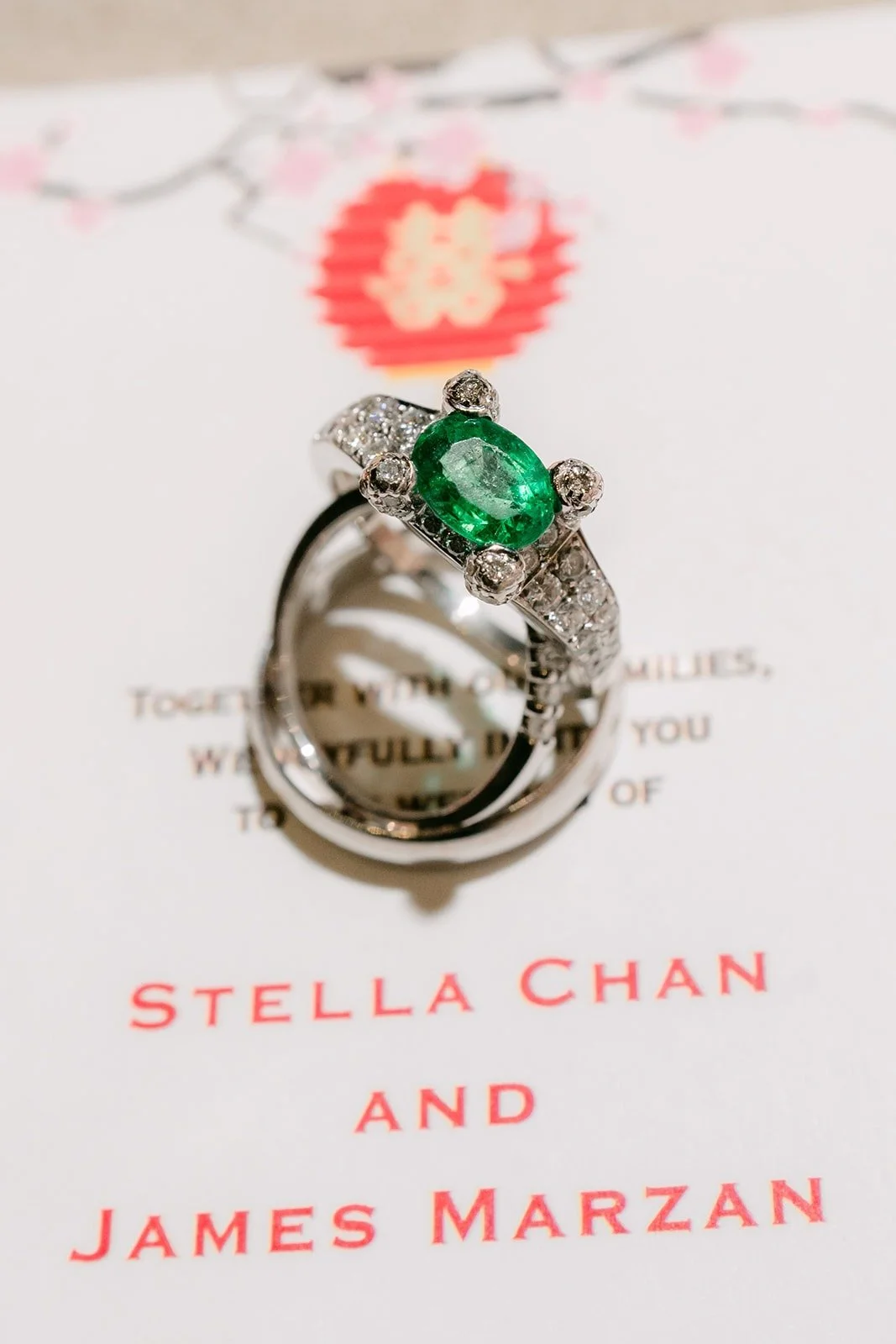 A green stone engagement ring set on the invitation printed with Stella and James's names