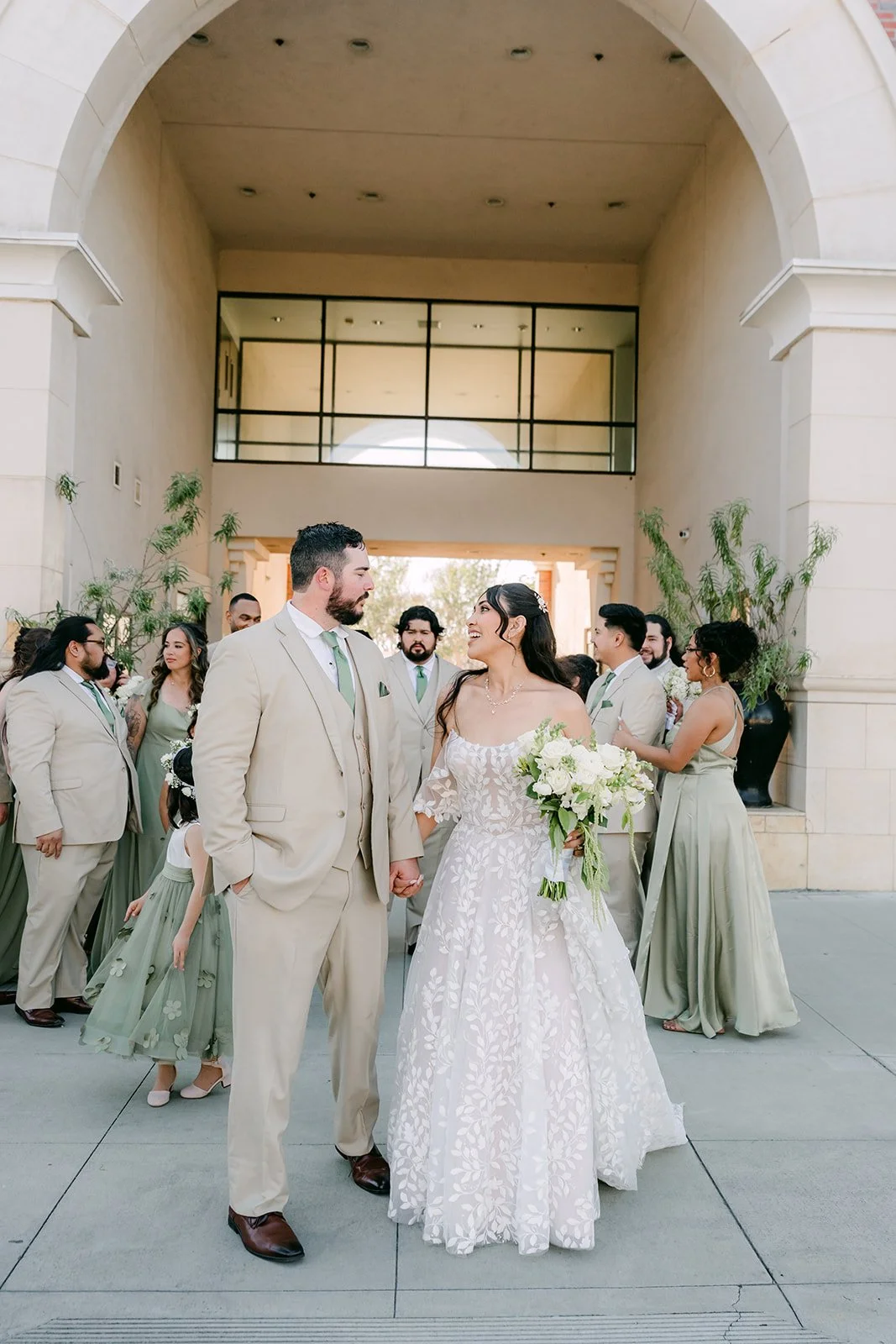 Fernanda and Cody walking under an arched entry with their wedding party.