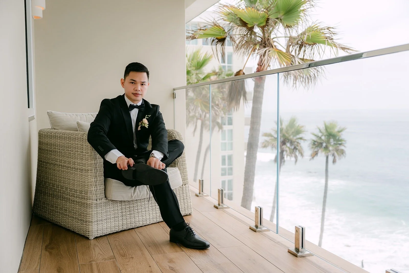 Mario sitting in a wicker chair with the palms and the beach behind him