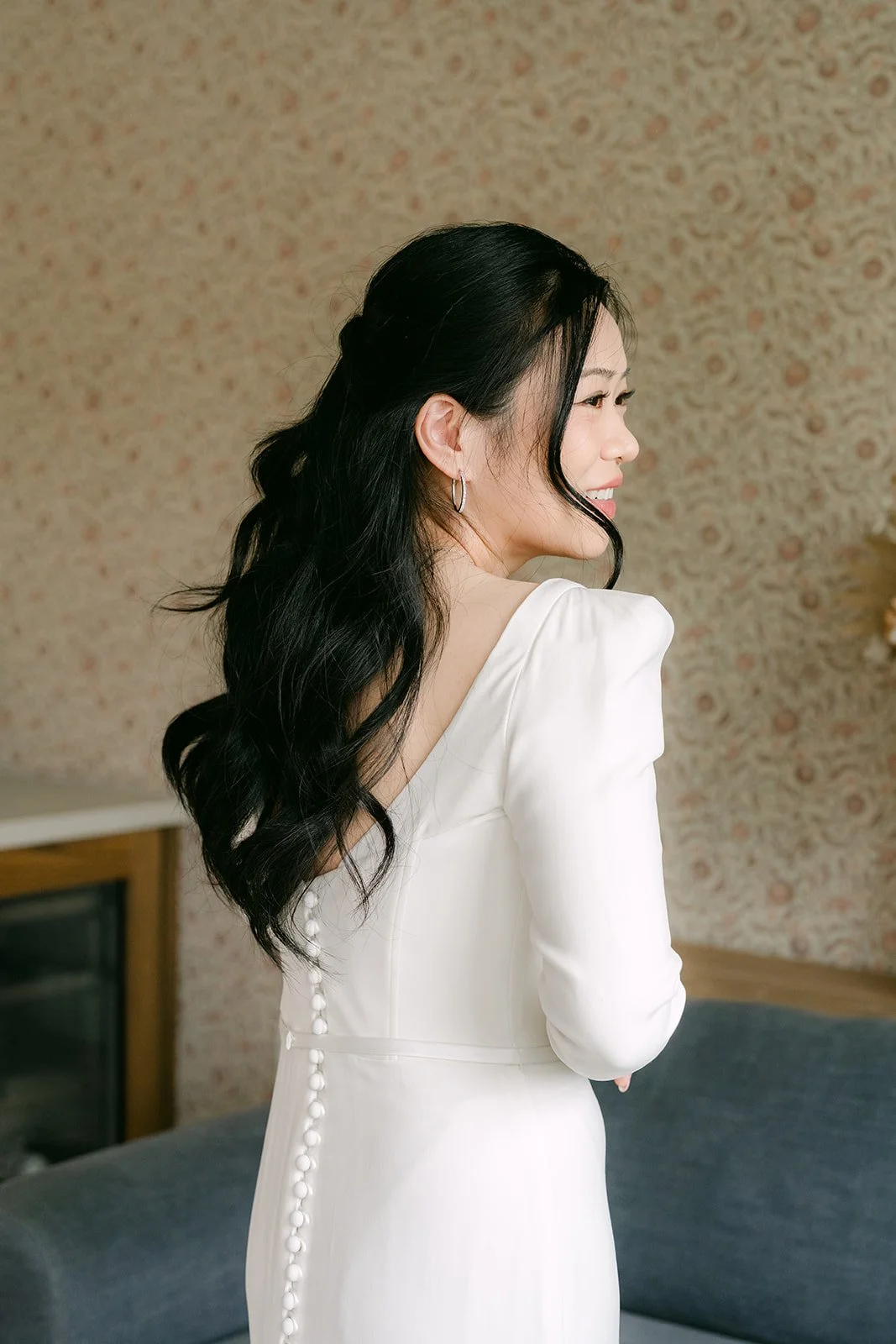 Denise glancing over her shoulder at the button back of her gown, photographed by One and Only Production.