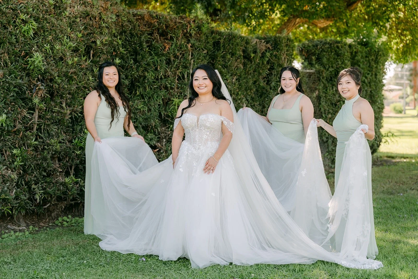 Jennifer's bridesmaids in sage green lift her train