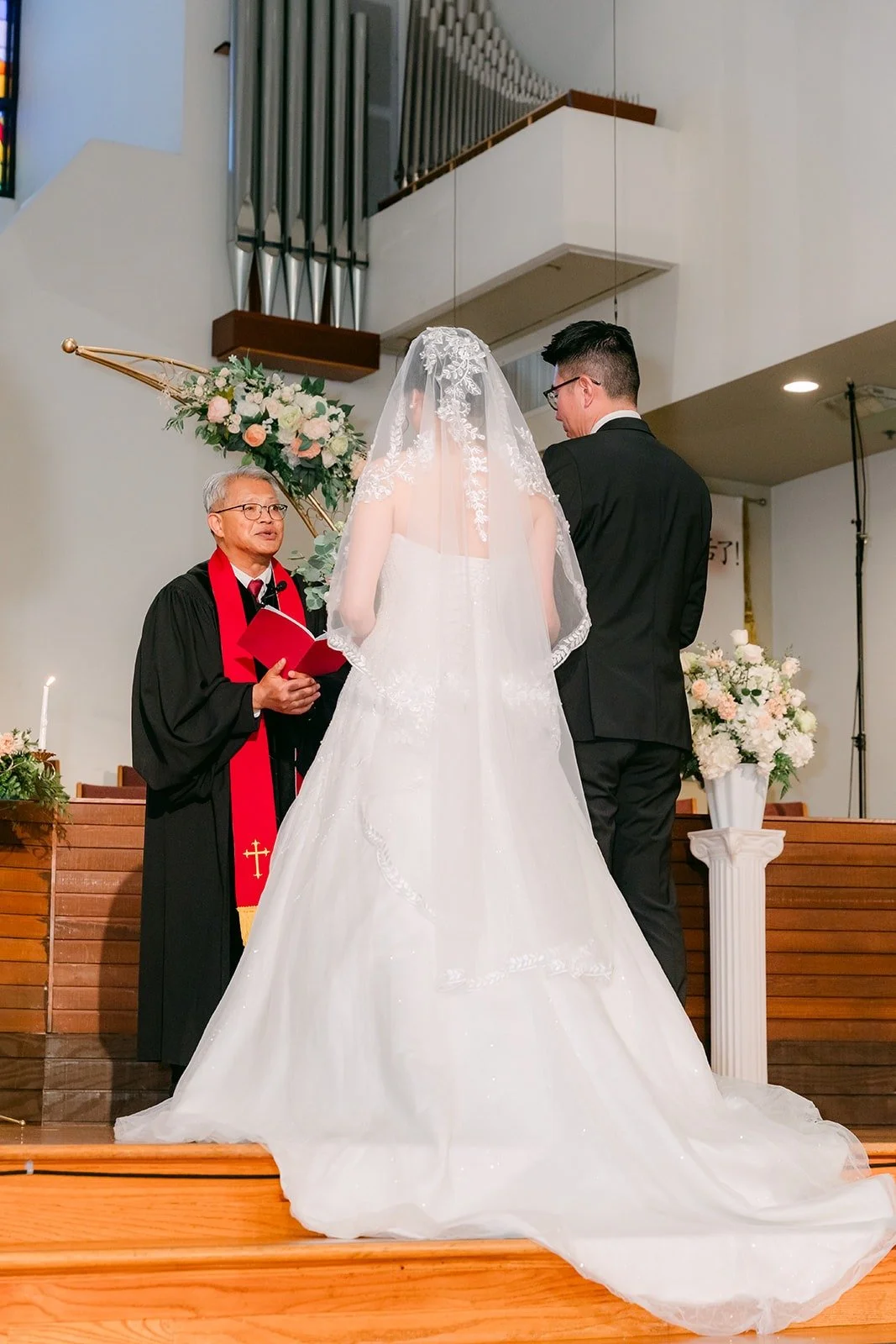 Eunice and Eric stand before the gold arch during the ceremony