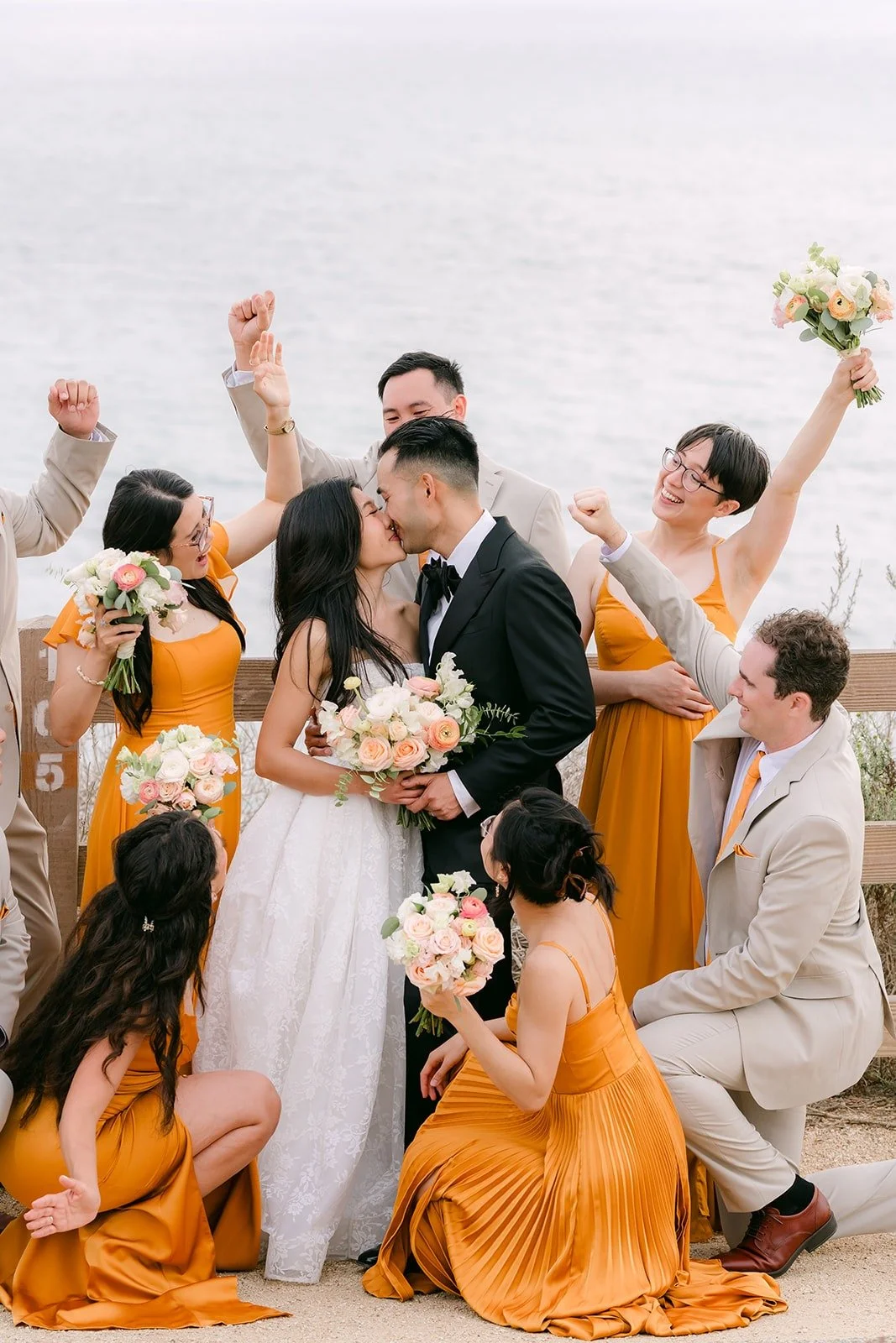 Bridesmaids and groomsmen cheering at the ocean overlook