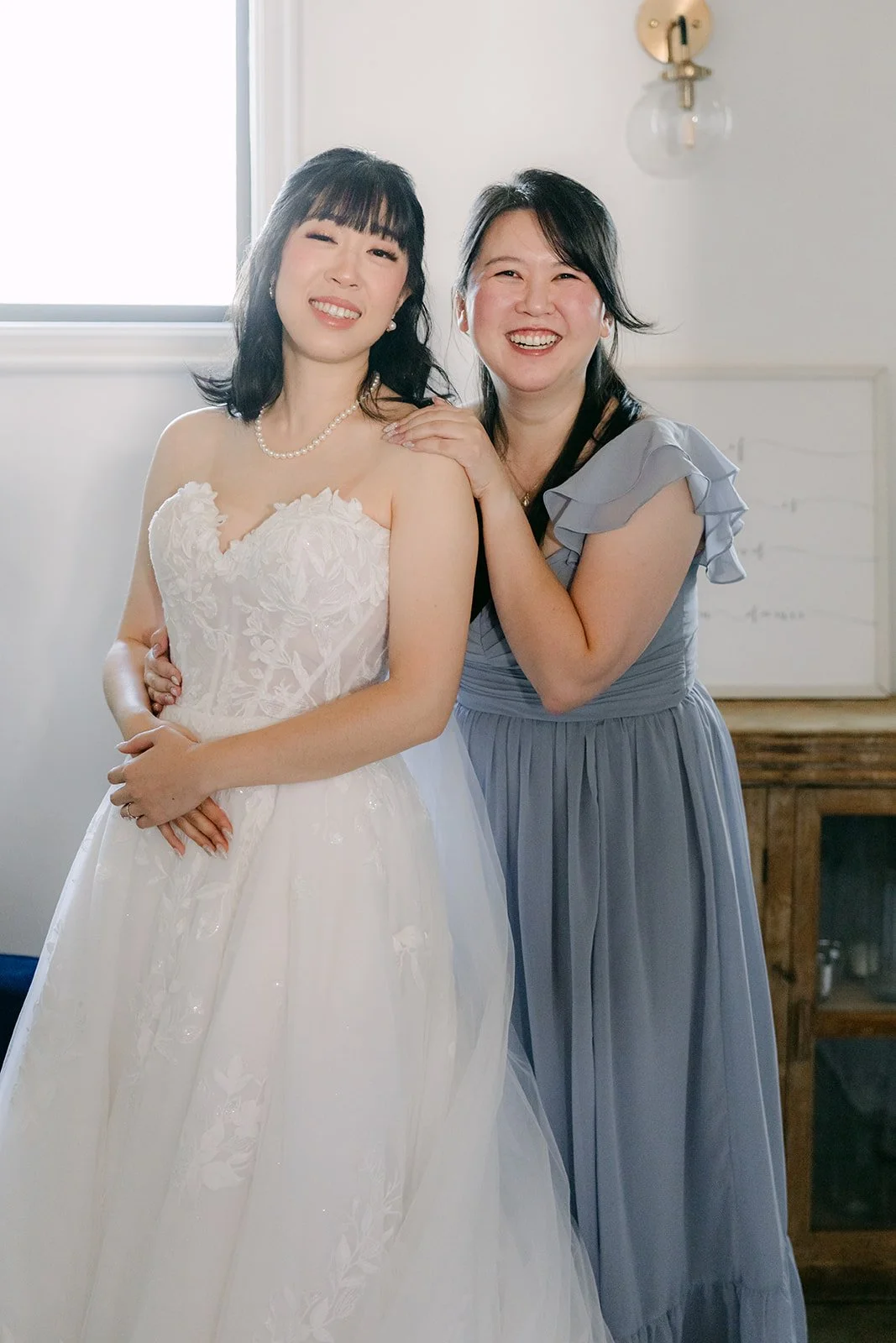 Vivian hugging a bridesmaid in dusty blue