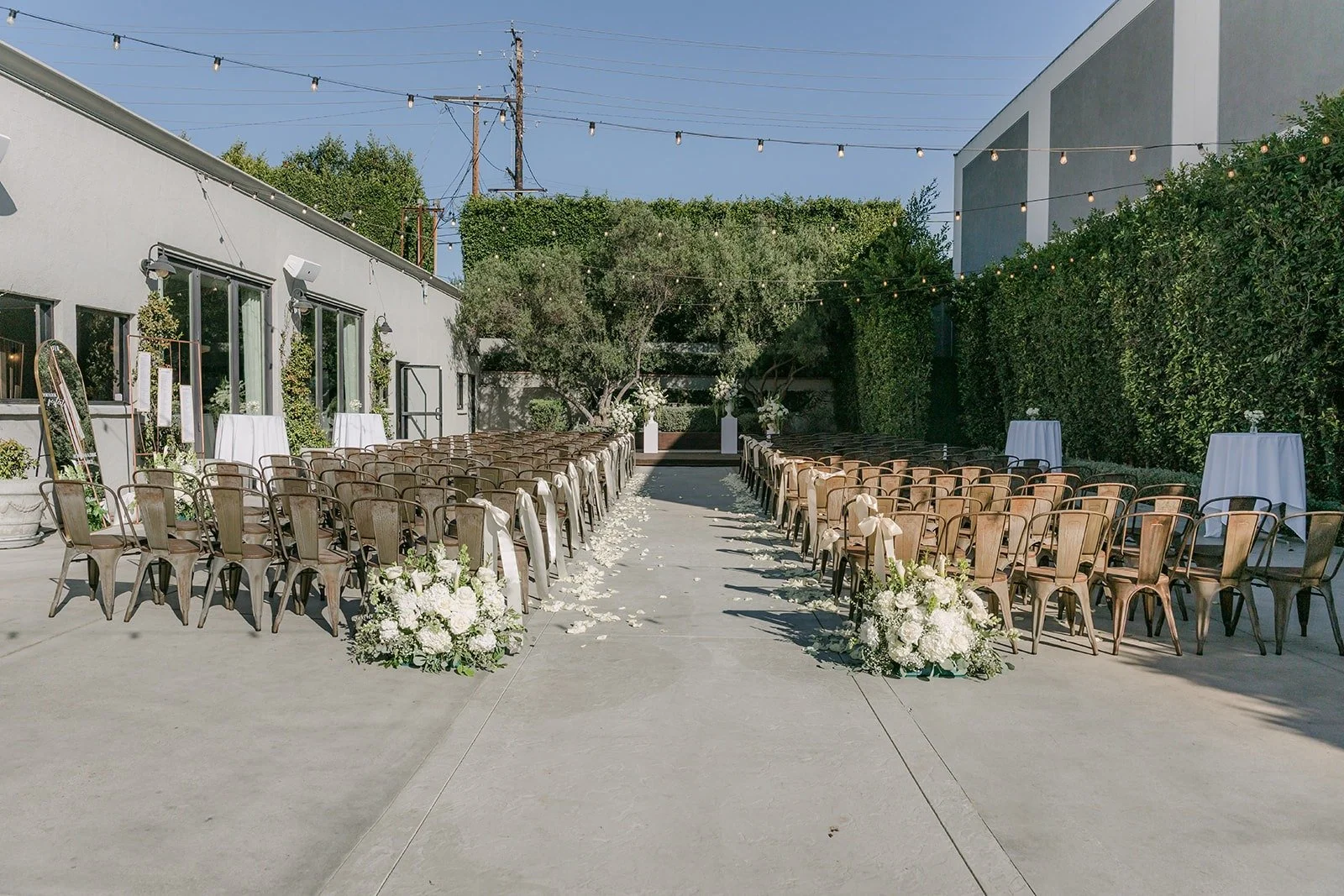 The ceremony aisle at The Harper lined with wooden chairs and white florals