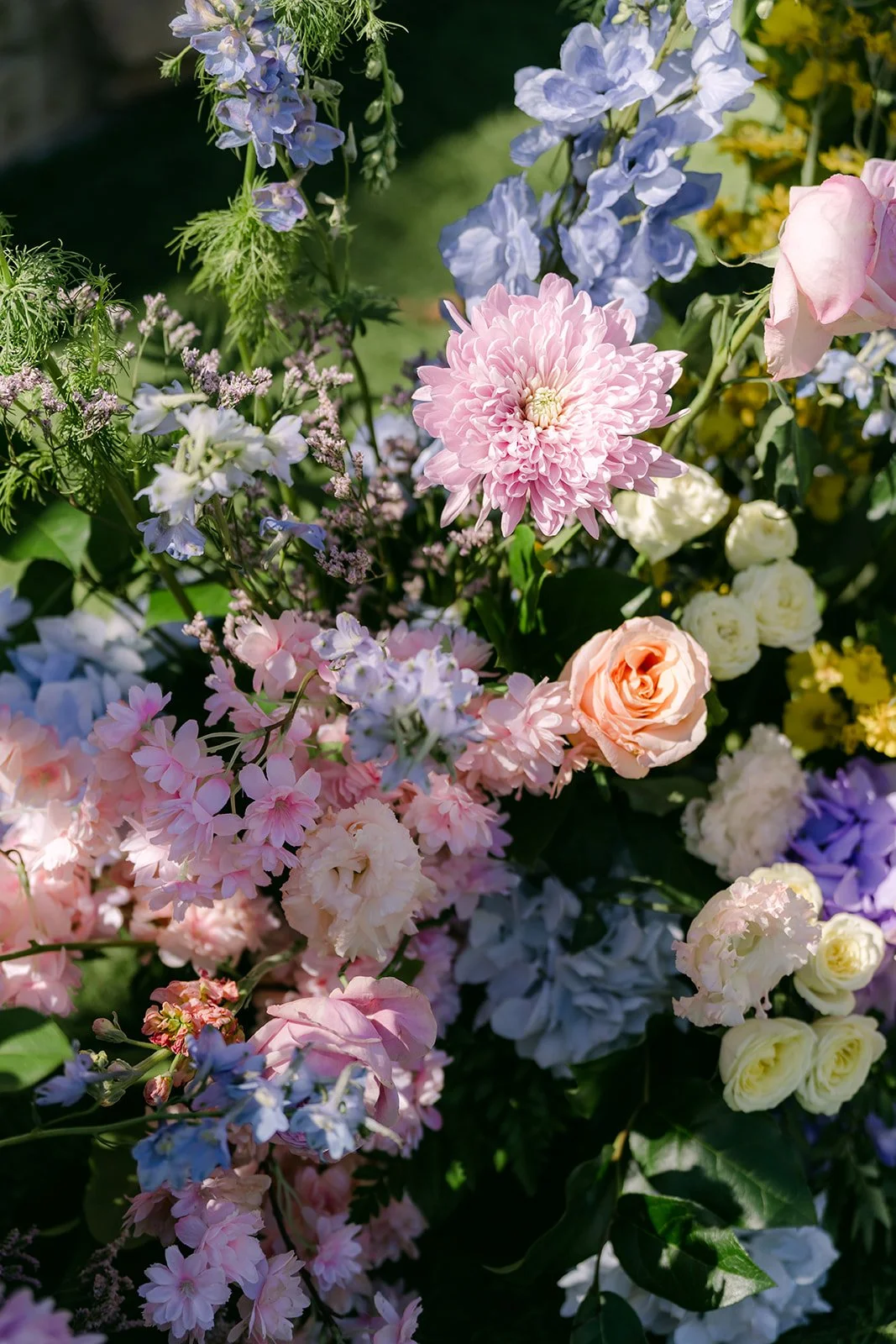 Pastel ceremony florals in lilac, blue, peach and blush lining the aisle.