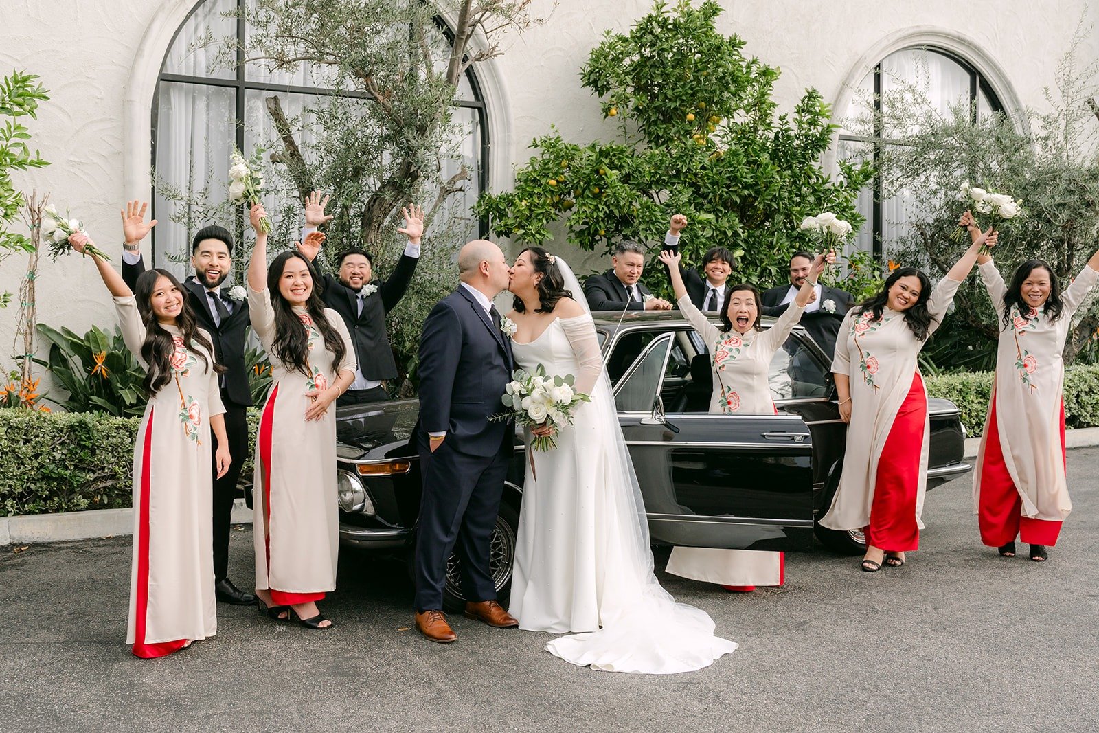 The bridal party cheering around the vintage car