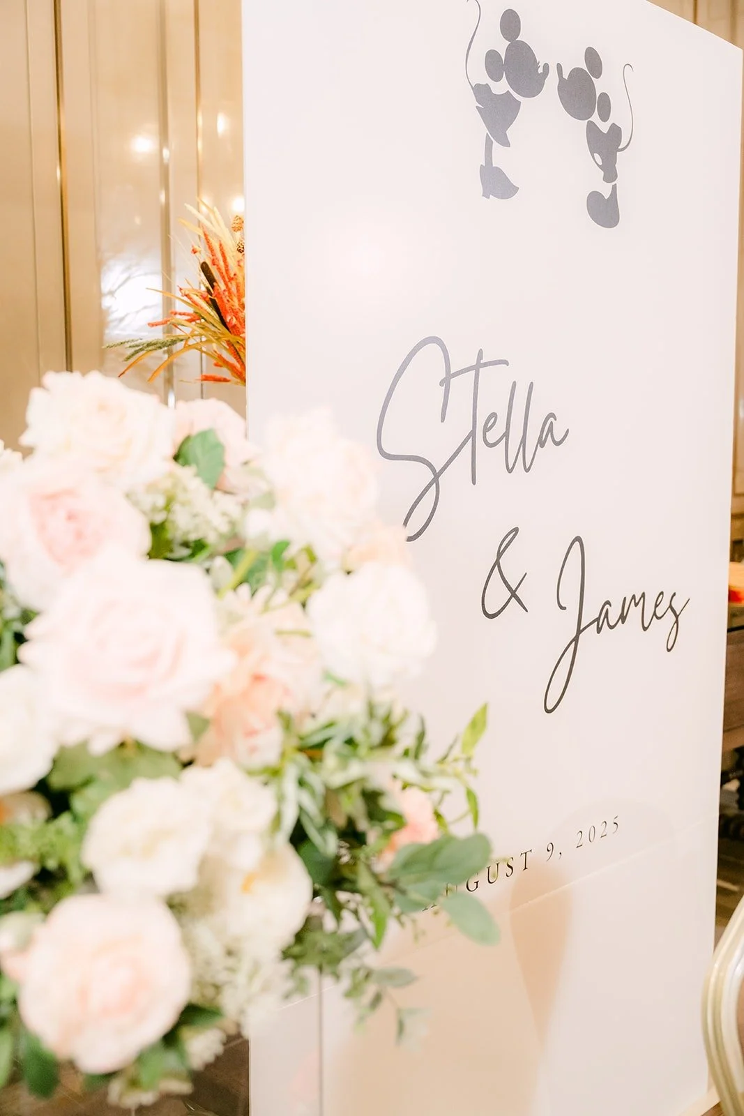 A welcome sign lettered Stella and James with Mickey and Minnie silhouettes beside white roses