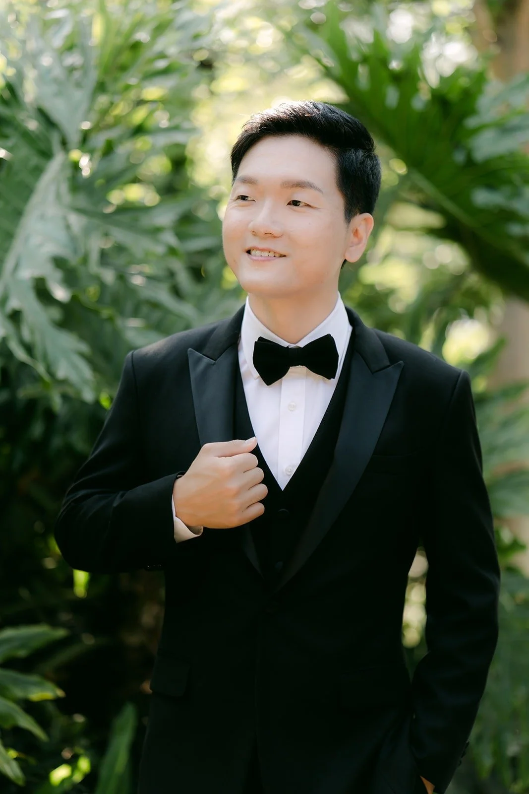 Eunsang smiling in his tuxedo against the palm leaves