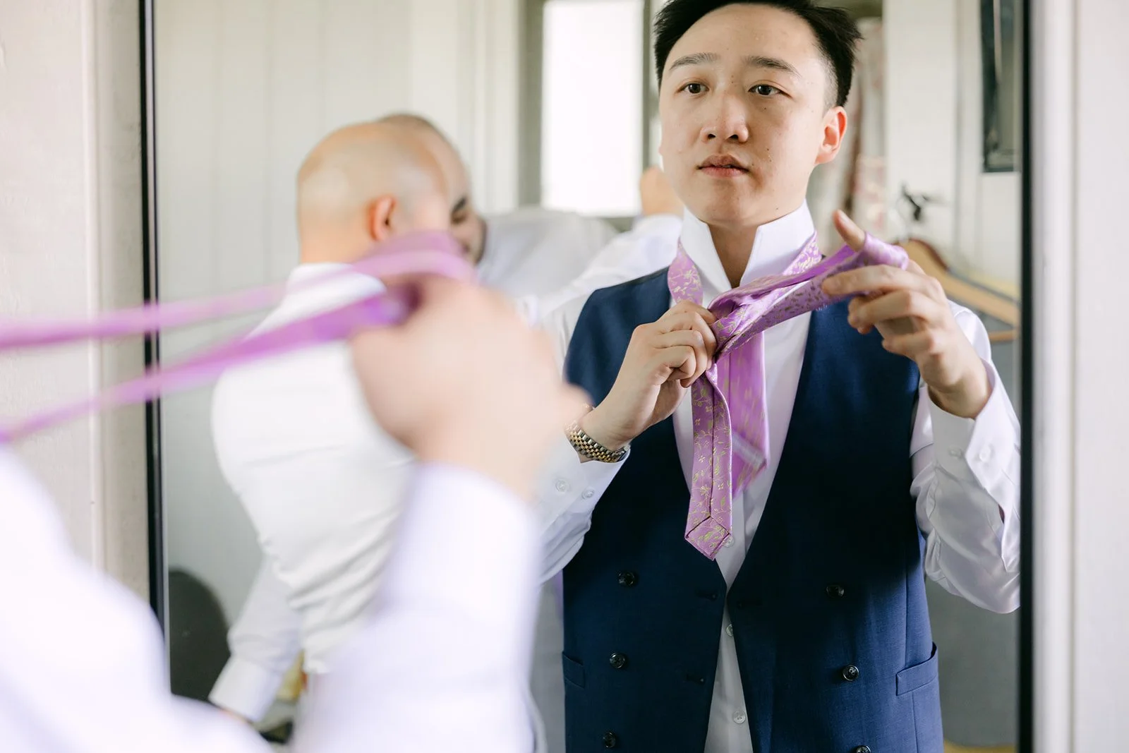 Groomsmen helping Elijah with his lilac tie.