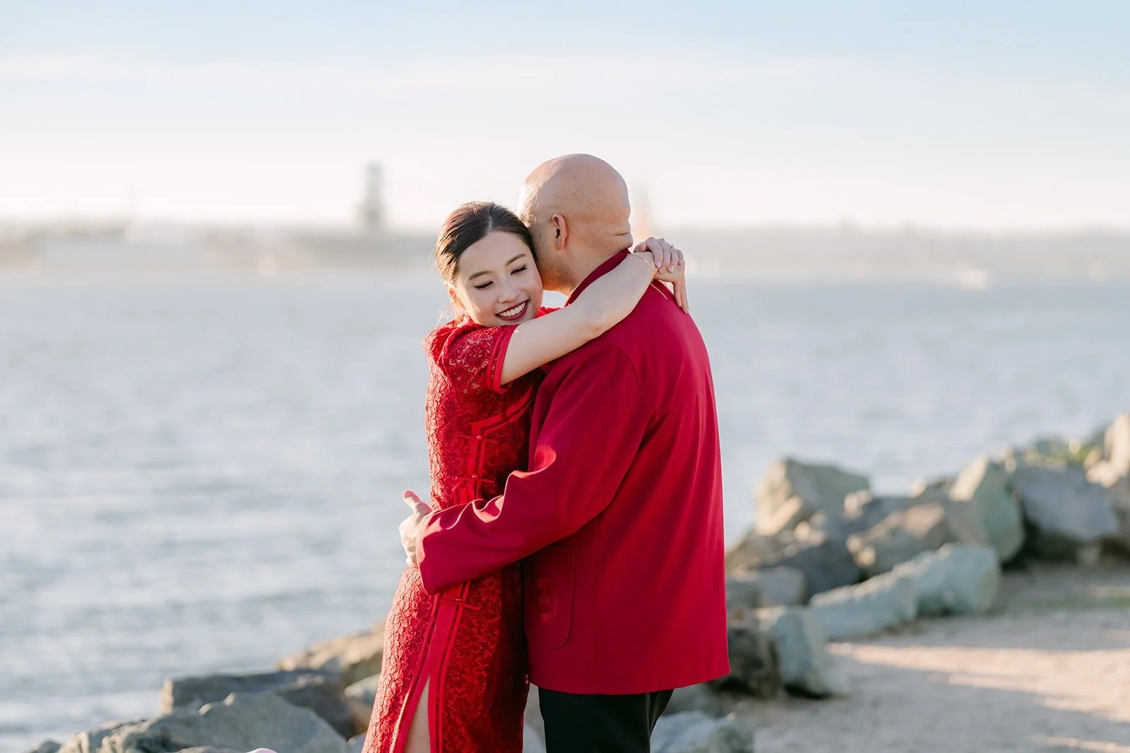 Brandon holds Elisa close by the rocks on San Diego Bay
