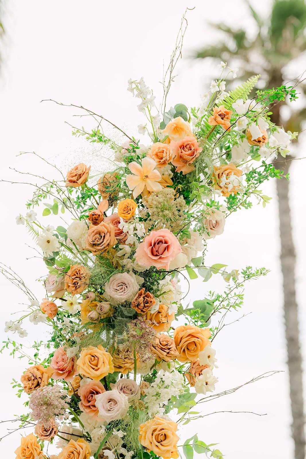 A tall column of peach and ivory florals against the sky