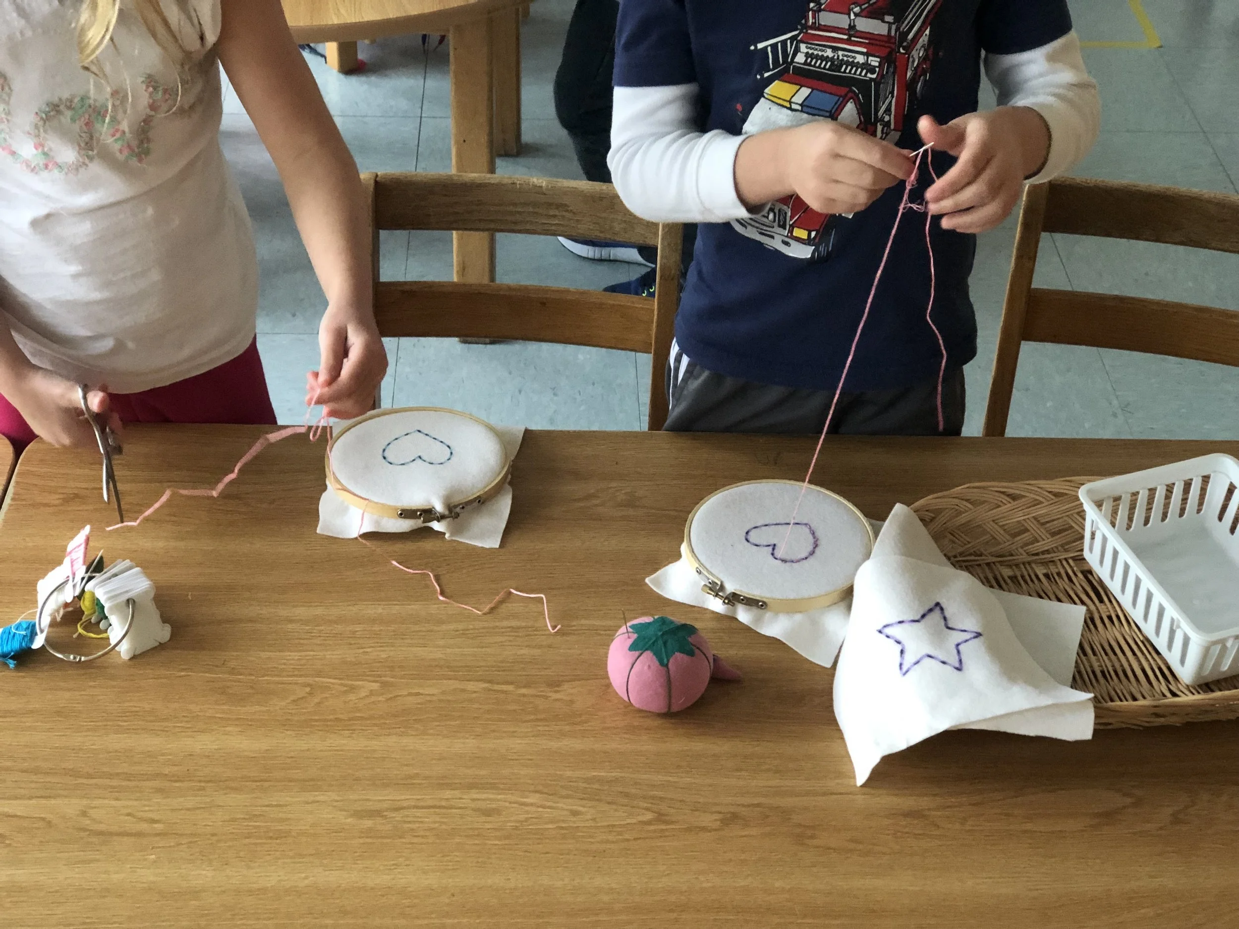 Two friends embroidering hearts onto felt.  