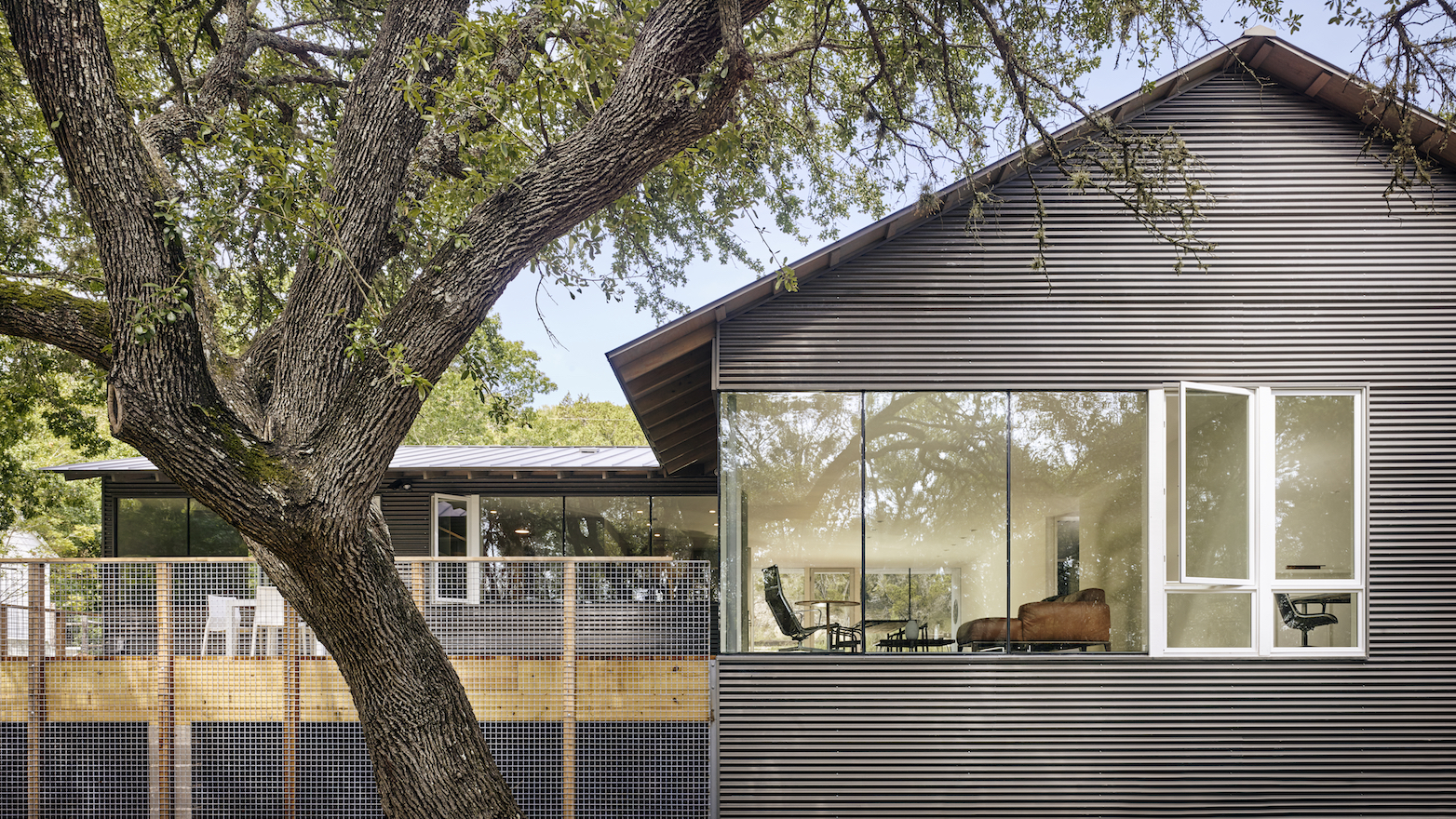 Where the house meets the ground, masonry piers are veiled behind galvanized welded wire panels and wooden posts making a place for vines to intertwine.