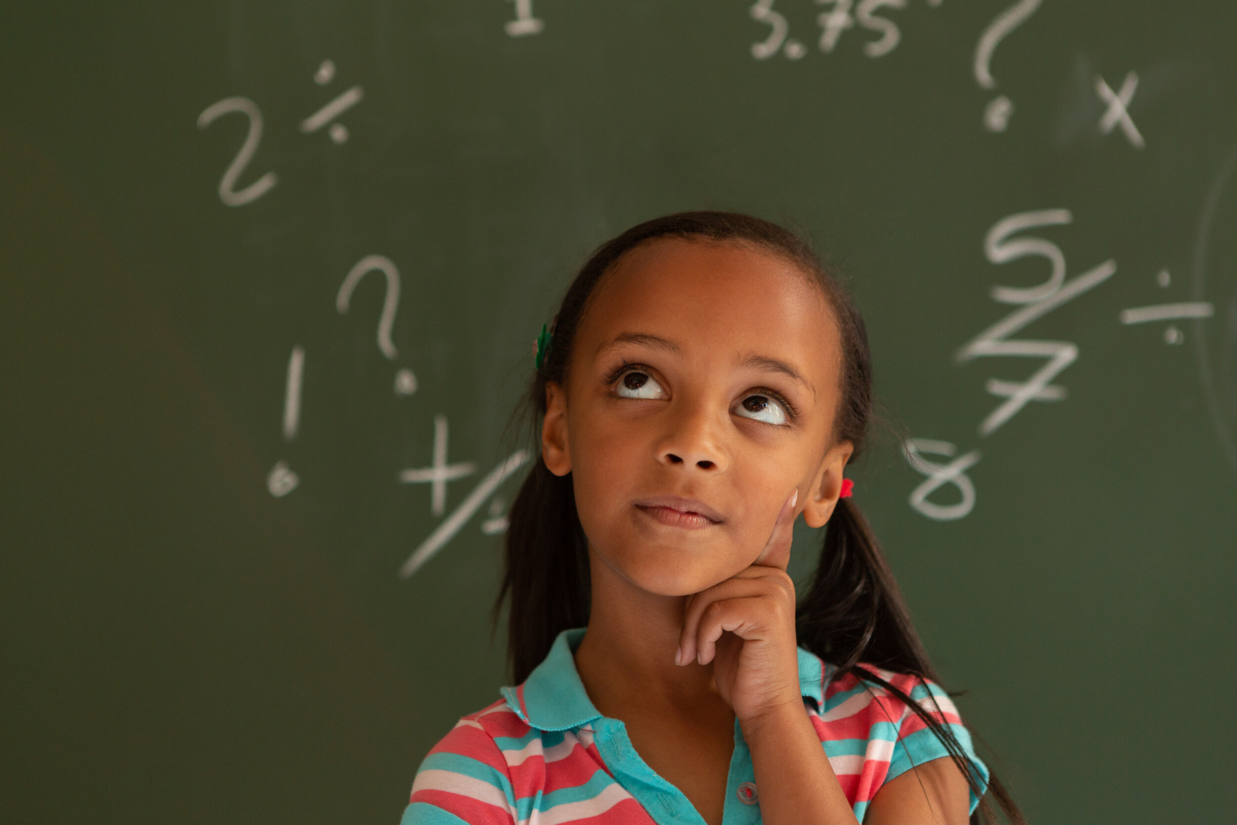 Schoolgirl standing against green board in a classroom at school