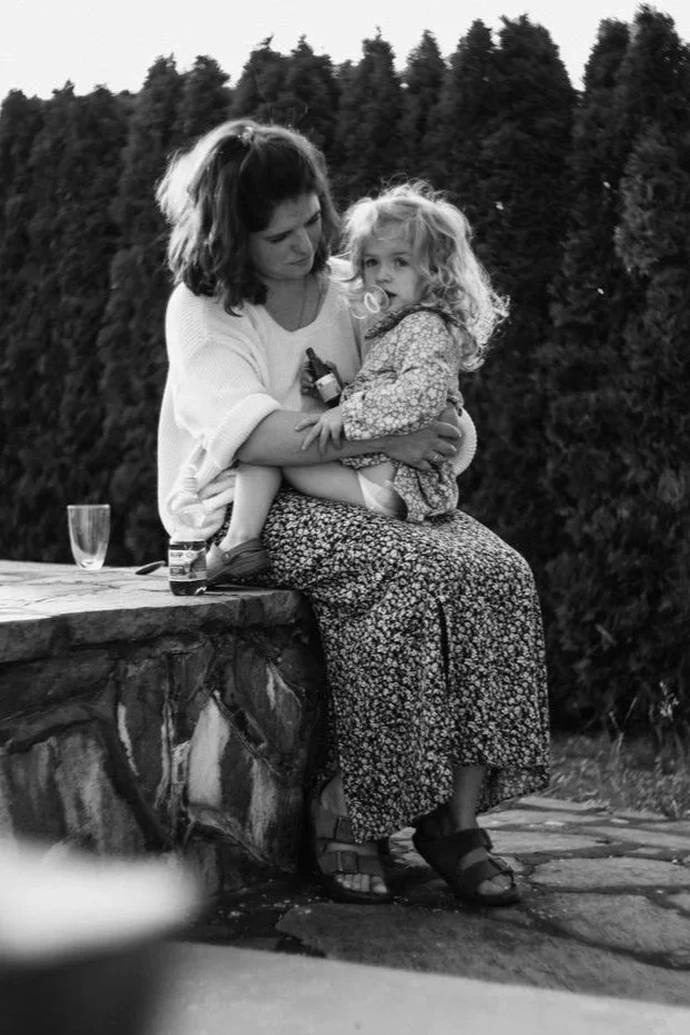 Eine Mutter sitzt mit ihrem Kind am Rande eines Steinpools. Die Aufnahme Schwarz-Weiß-Aufnahme wirkt zeitlos und verträumt.