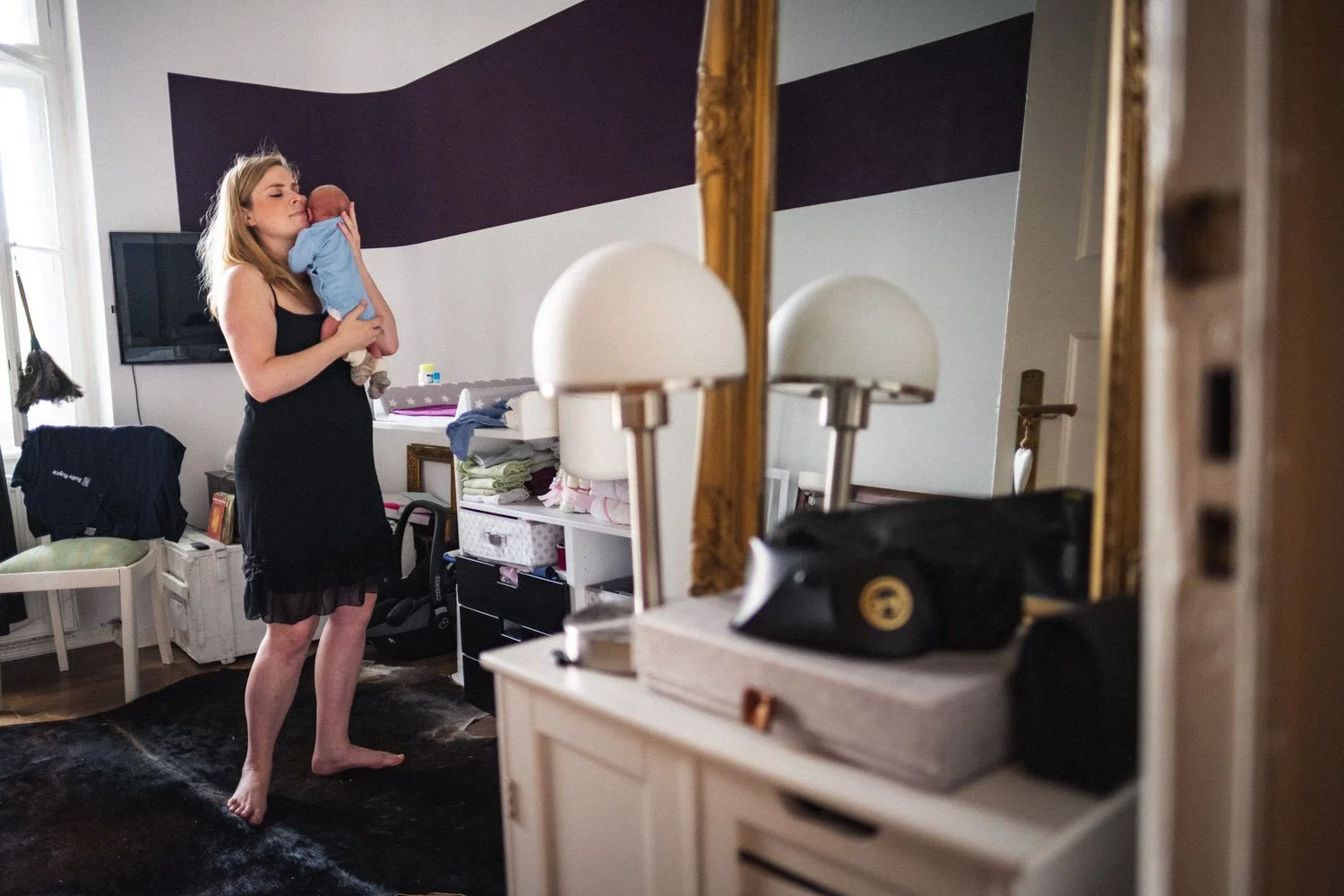 Eine Frau hält in einem ruhigen Moment ein schlafendes Baby  in einem stilvoll und klassisch eingerichteten und Zimmer.