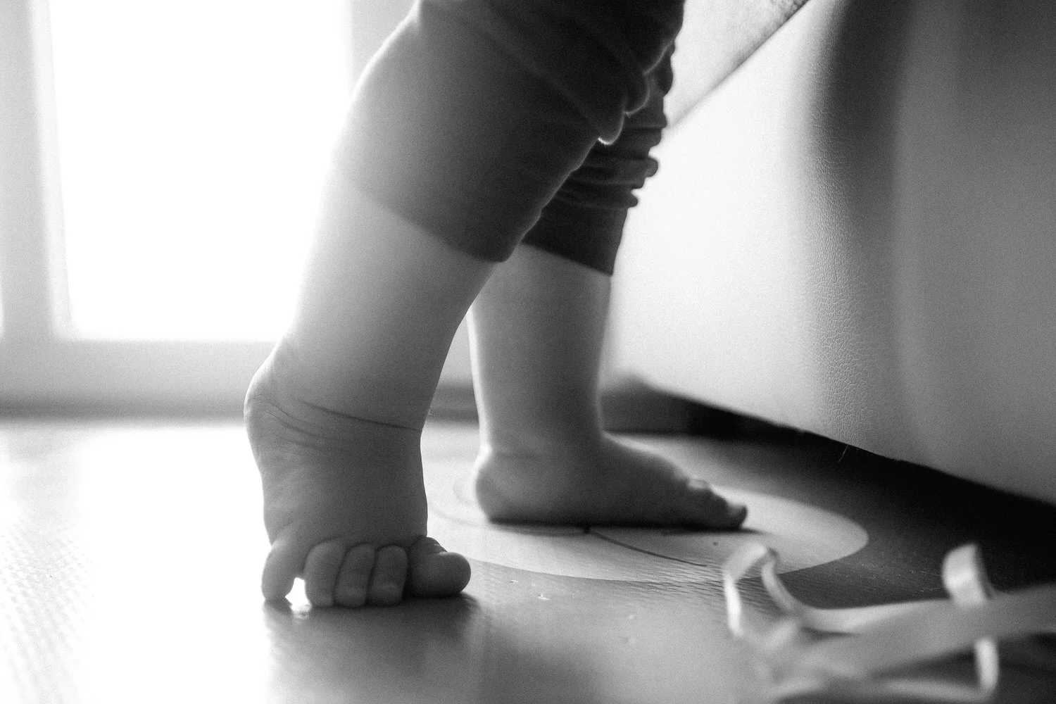 Nahaufnahme eines Kindes, das auf Zehenspitzen steht, in schwarz-weiß aufgenommen.