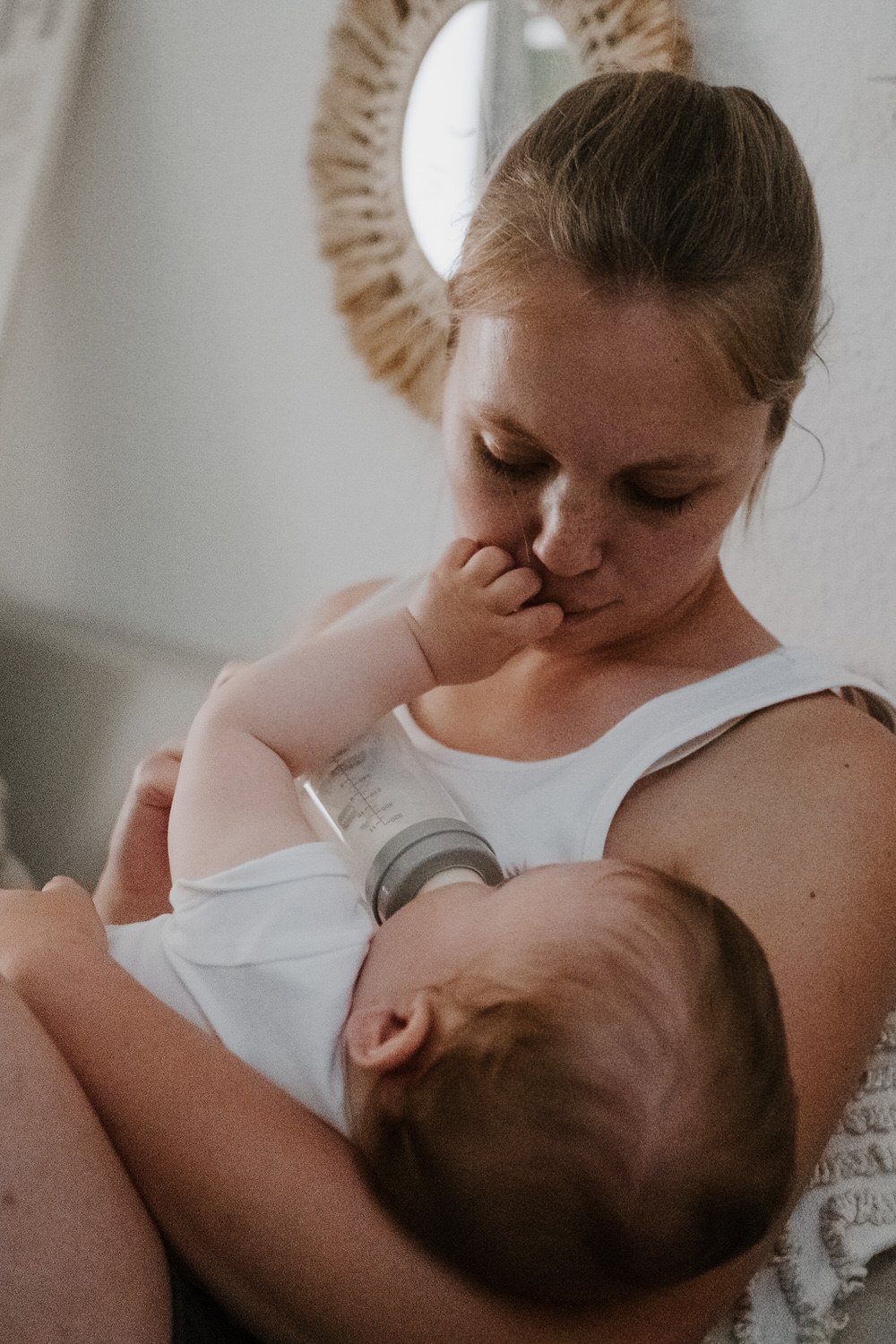 Eine intimer Moment, in der eine Frau ein Baby mit der Flasche füttert, das auf ihrem Arm liegt.