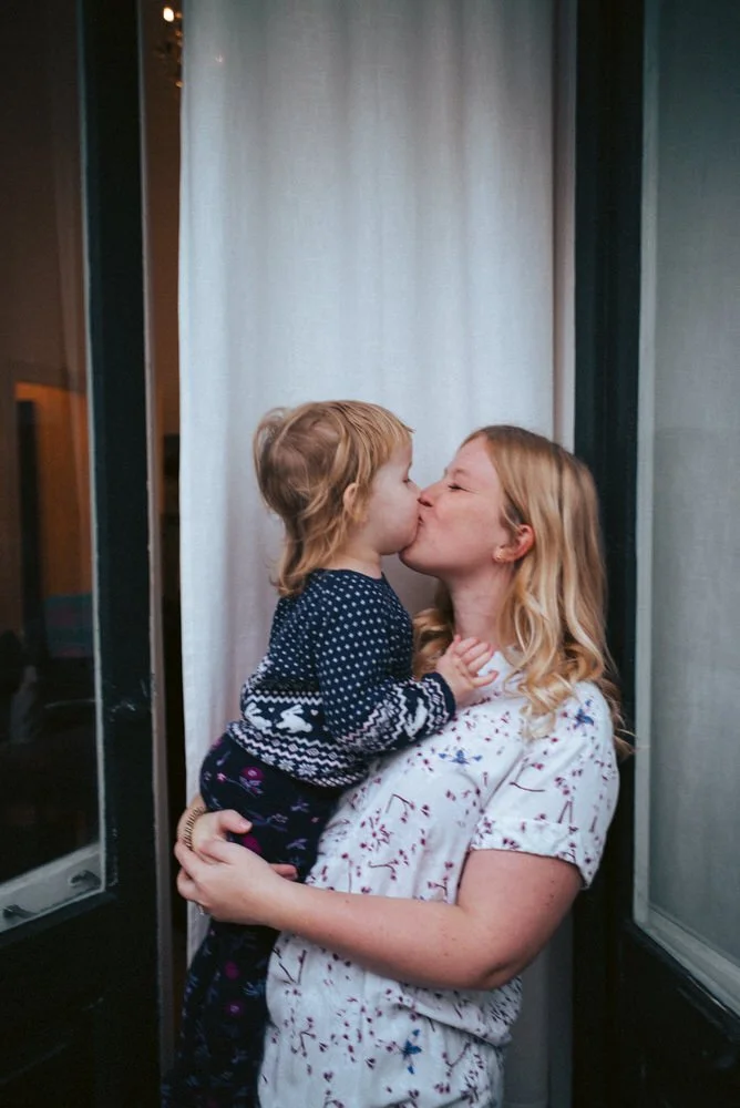 Eine Frau hält ein kleines Mädchen, und sie küssen sich liebevoll.