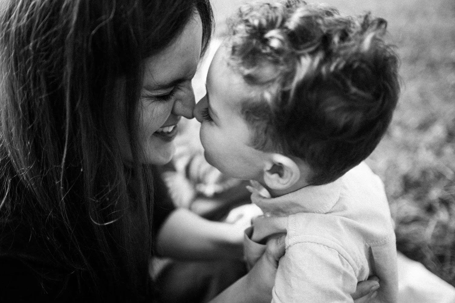 Mutter und Sohn, die sich mit ihren Nasen berühren, lachen und Freude zeigen, in einer Nahaufnahme in Schwarz-Weiß.