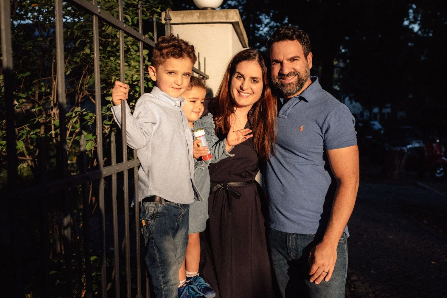 Familienreportage: Familie mit zwei Kindern steht draußen bei Sonnenuntergang, lächelt in die Kamera.