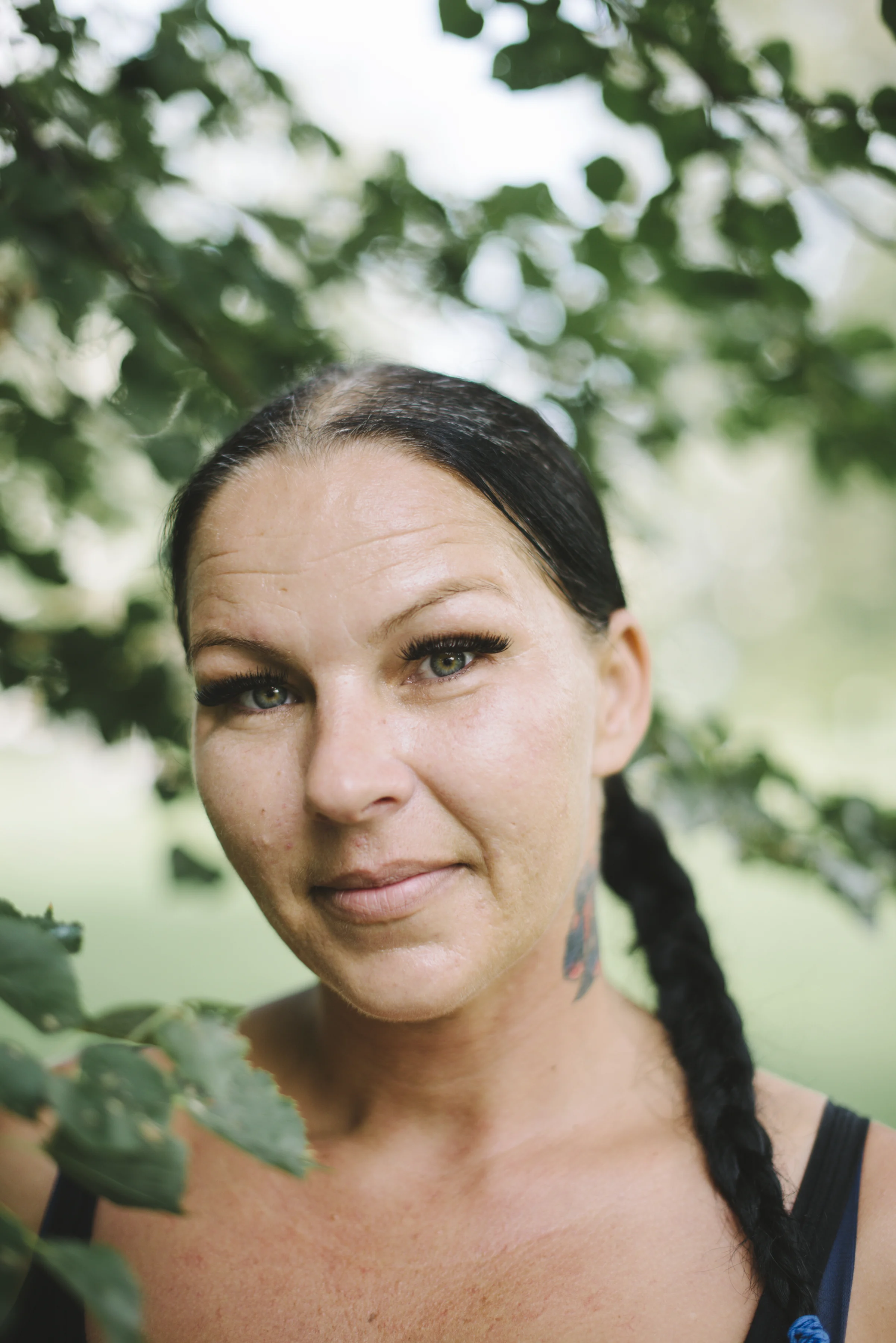 Close outdoor portrait of a woman with lush greenery around her, looking softly into the camera in Toronto