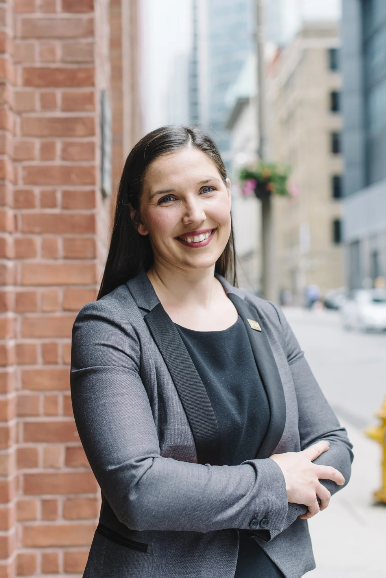 Outdoor branding portrait of a woman against a brick exterior and urban street backdrop in Toronto