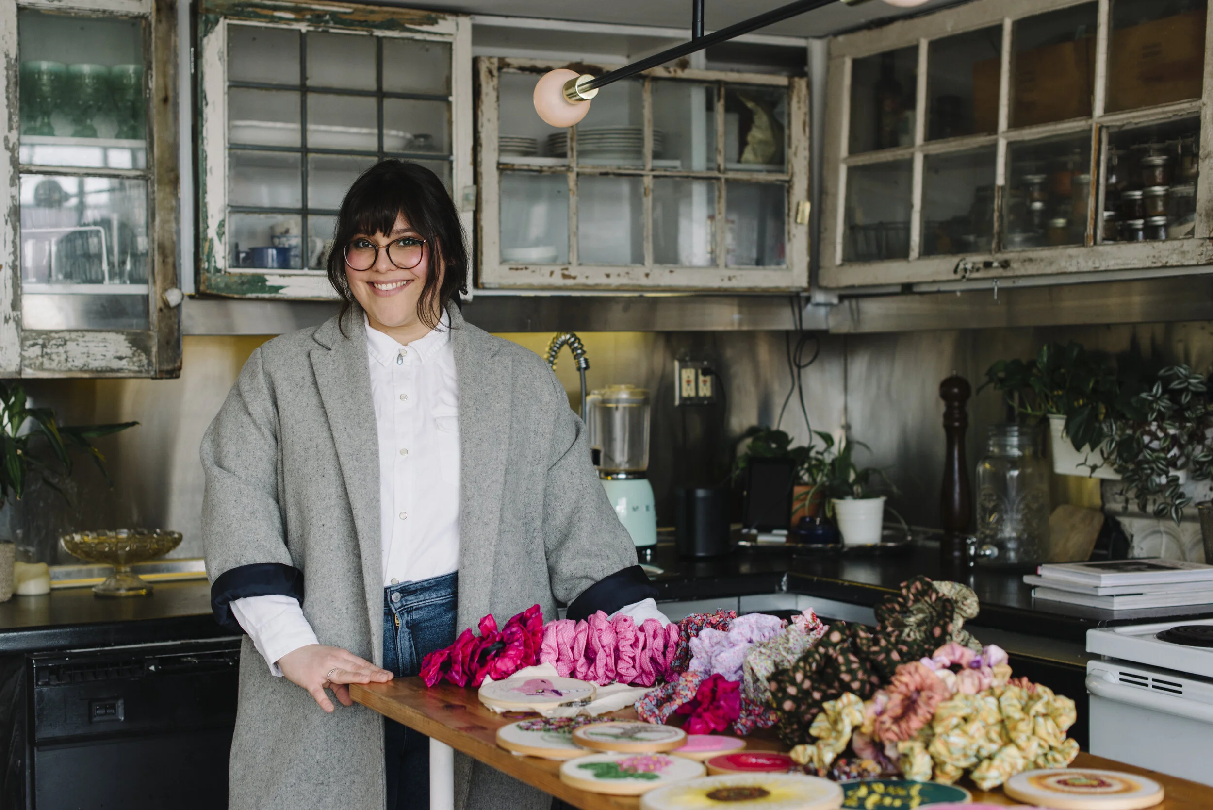 Branding portrait of Sew Solange standing in a stylish industrial loft kitchen surrounded by her handmade craft collection