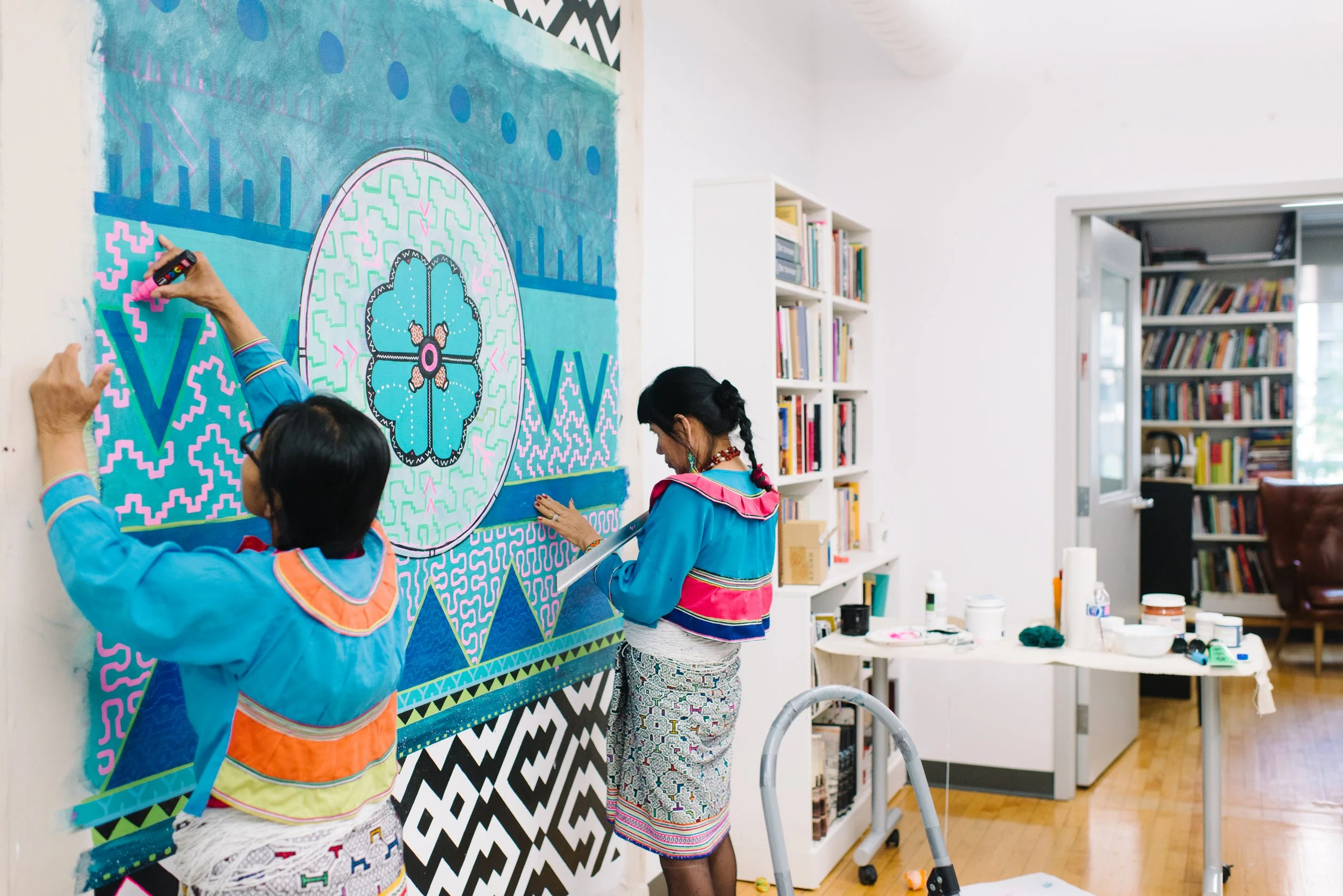 Wide documentary photo of Olinda Reshinjabe Silvano and her team working together on the large scale public mural at TMU in Toronto