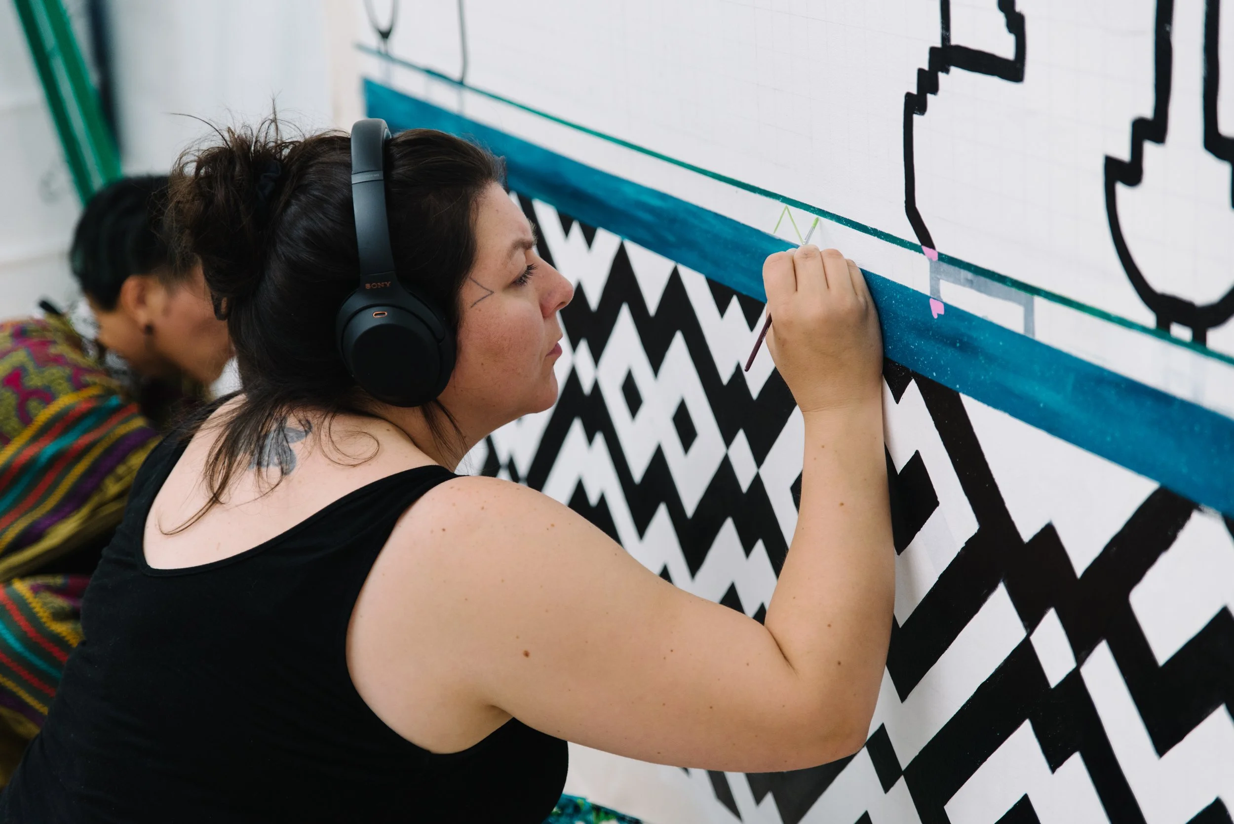 Close up portrait of Arctic artist Niap (Nancy Saunders) at work on the Arctic/Amazon public mural at Toronto Metropolitan University