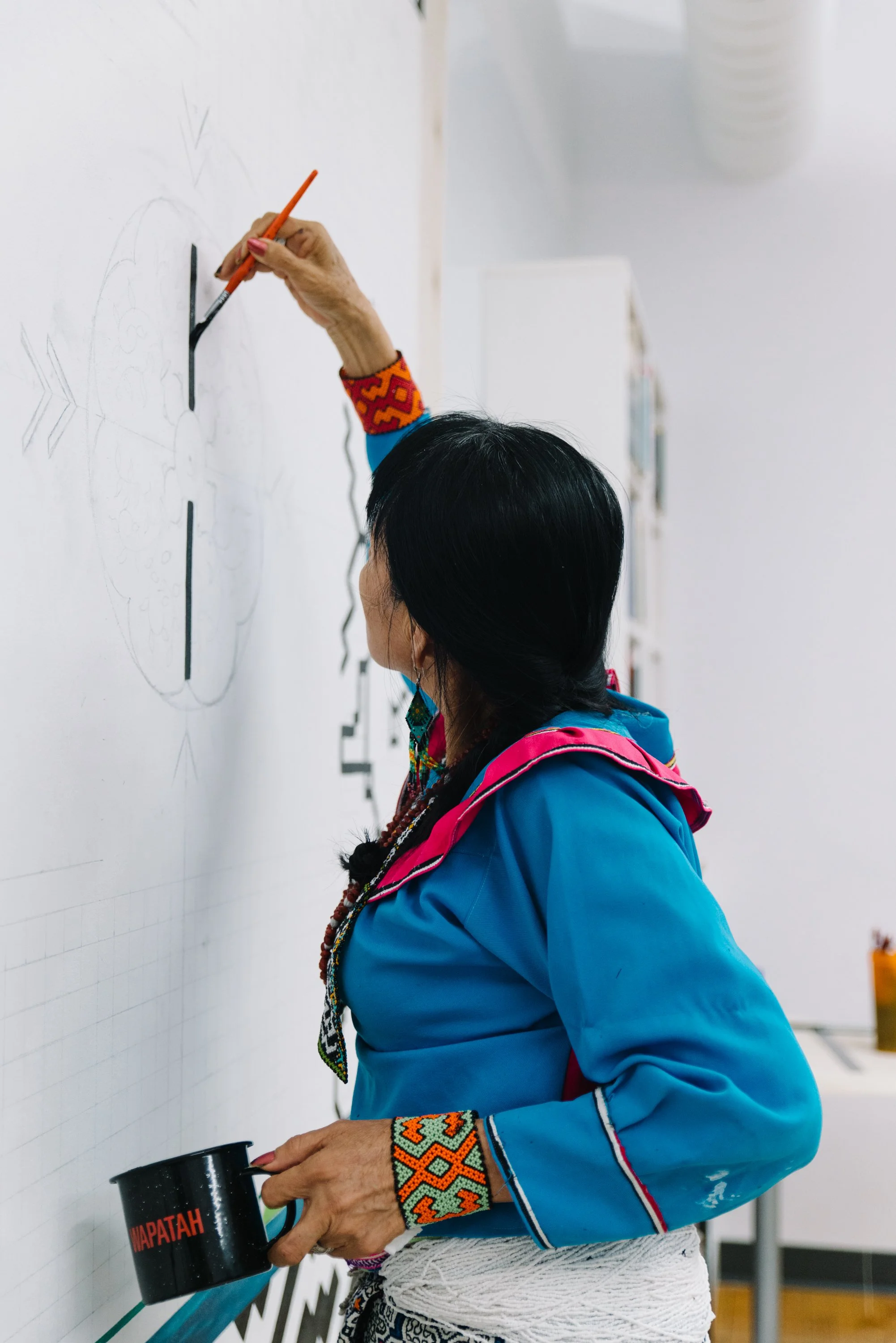 Close portrait of Amazon artist Olinda Reshinjabe Silvano working on the Arctic/Amazon mural at TMU in Toronto