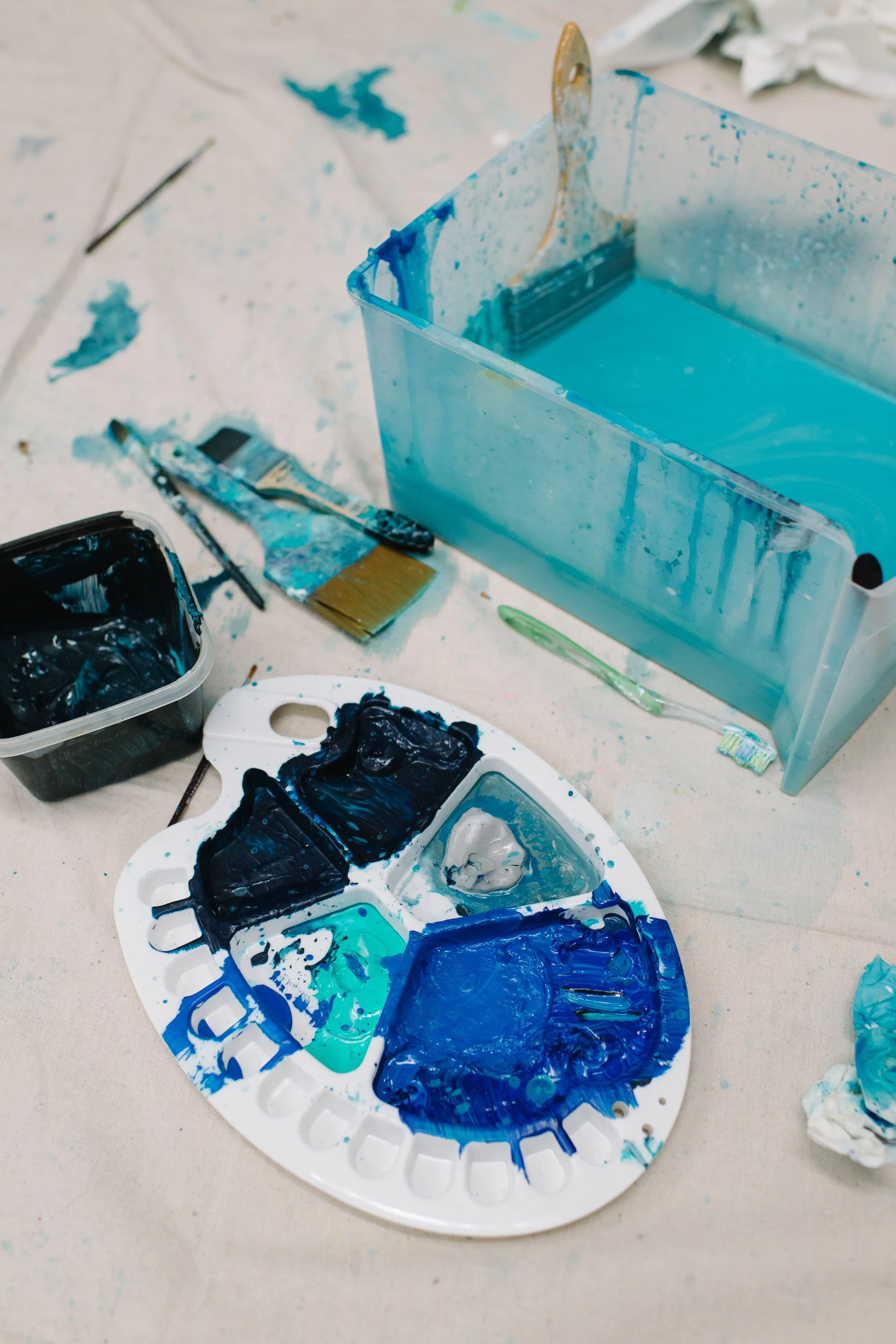 Detail photo of blue paint supplies arranged on the ground during the creation of the Arctic/Amazon public mural at Toronto Metropolitan University