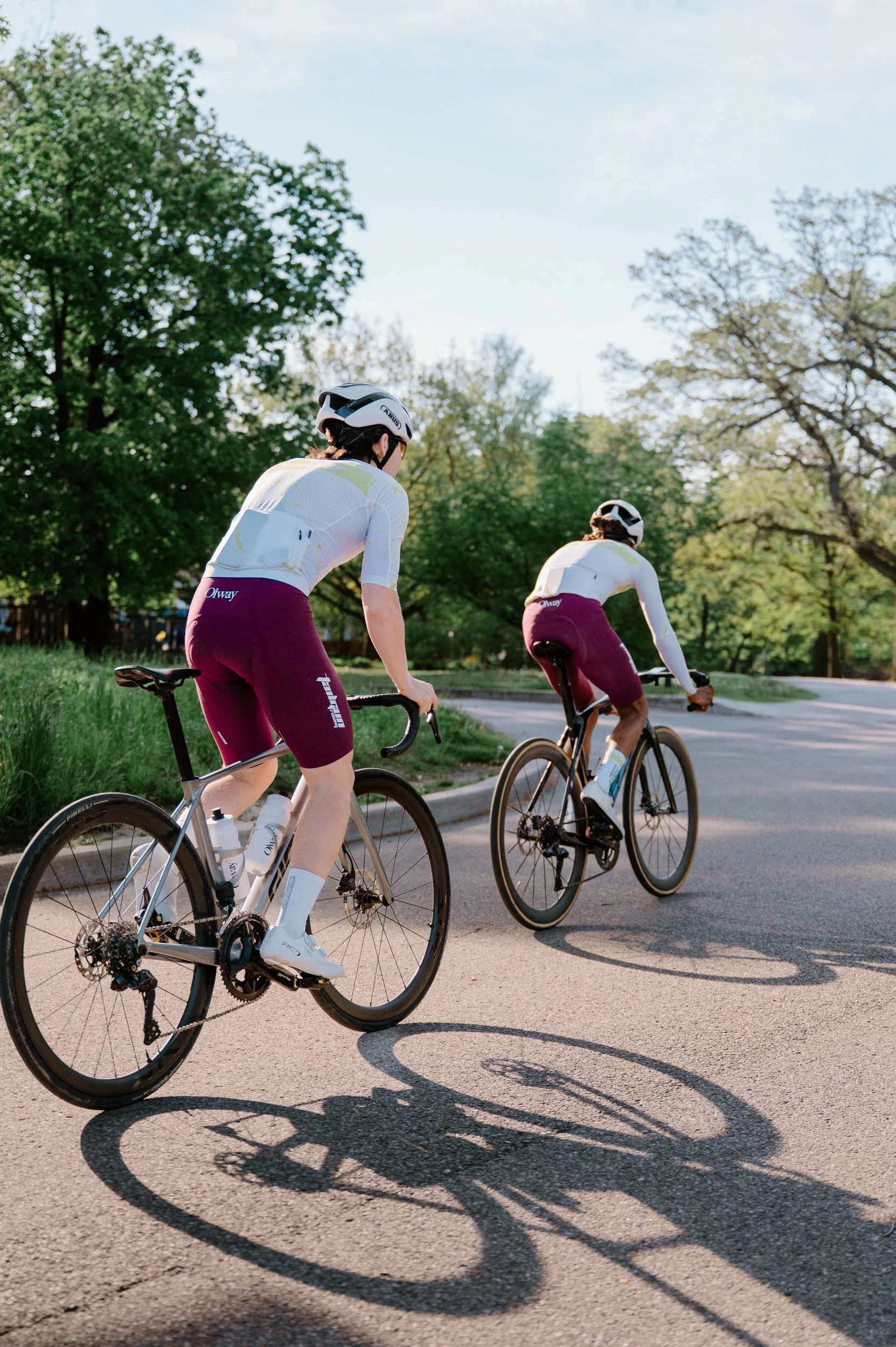 Two road cyclists climbing a hill from behind in High Park Toronto, one rider standing out of the saddle